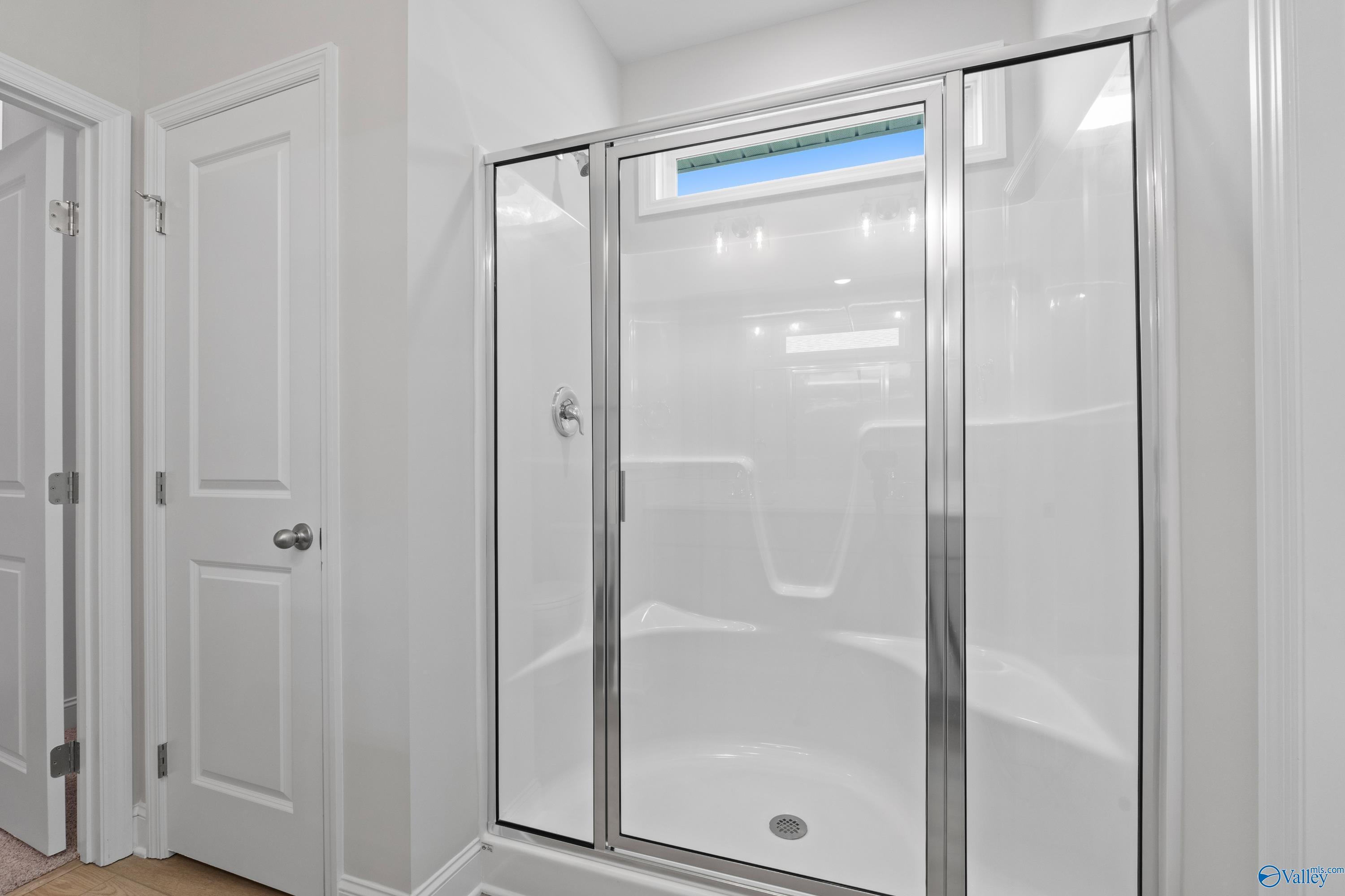 Elegant white glass shower with transom window in master bath of The Asheville home by Davidson Homes, Spragins Cove, Huntsville