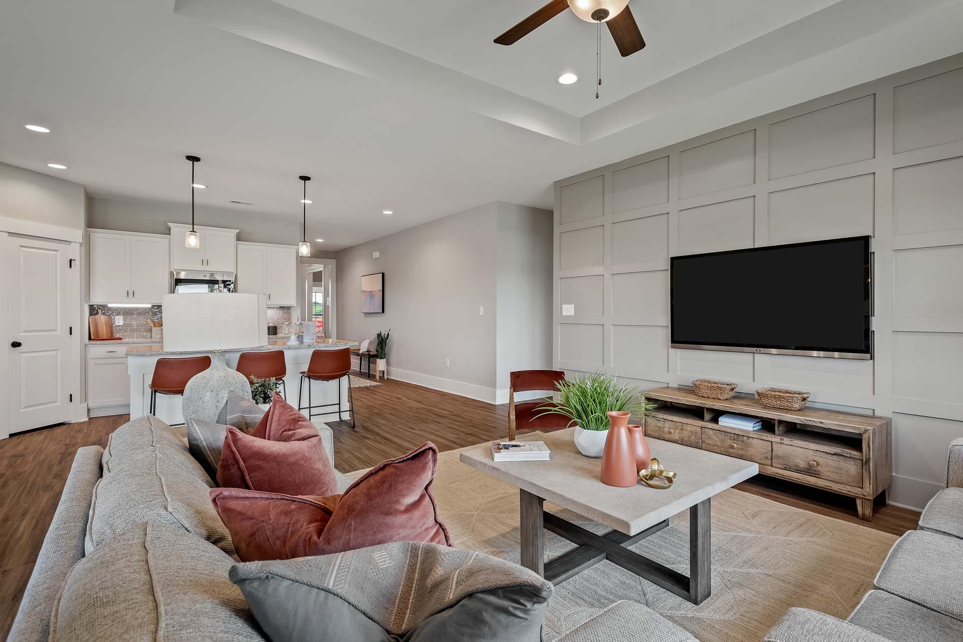 Open-concept living room and kitchen in Heritage Lakes New Market Alabama with hardwood floors shiplap walls TV and cozy sectional