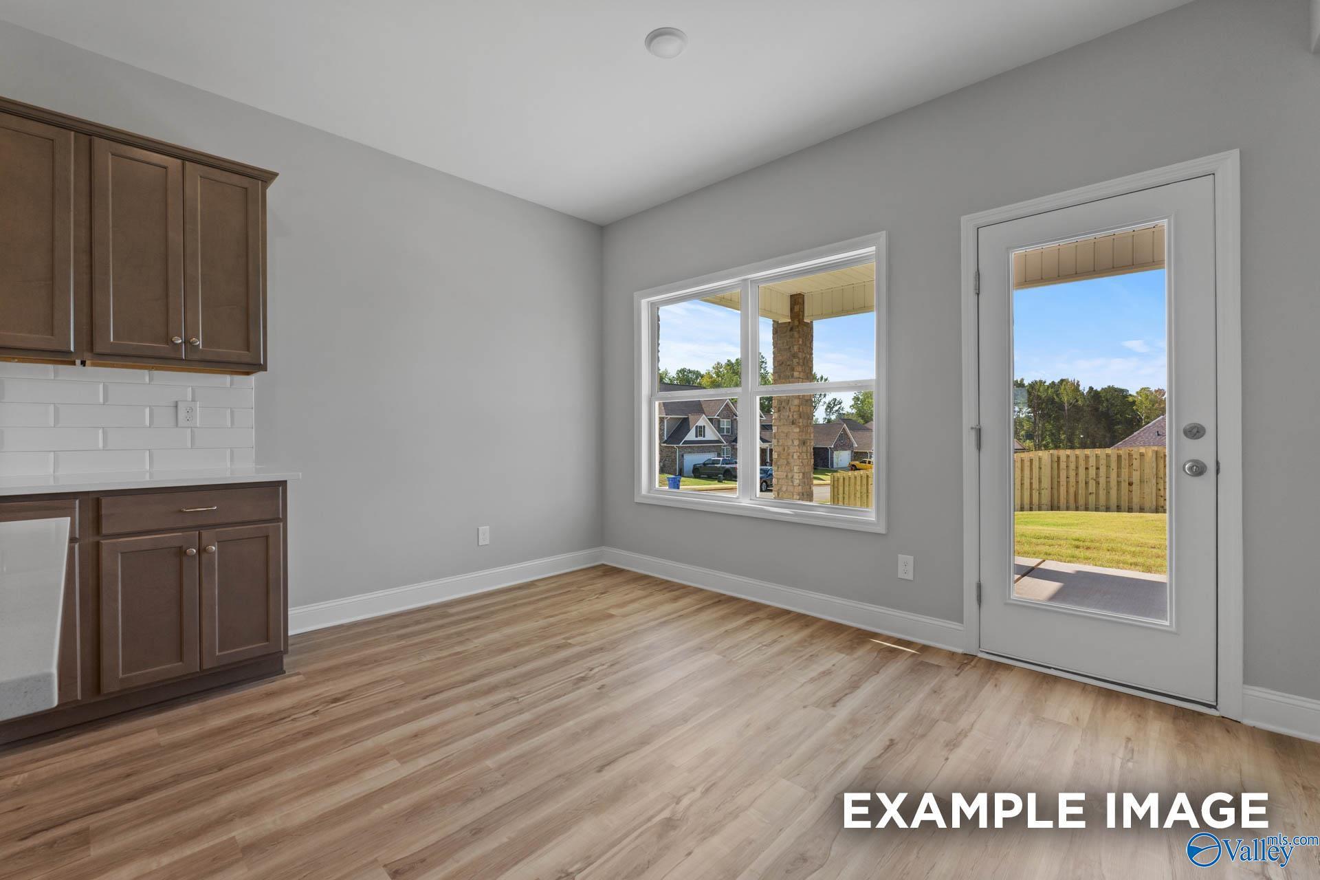 Bright breakfast area with wood-look flooring and backyard access in The Shelby B floor plan at Creek Grove, New Market.