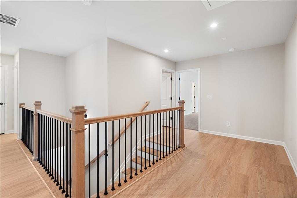 Upstairs landing with oak staircase, black metal balusters, and hardwood floors in Davidson Homes The Marion A, Kennesaw, GA