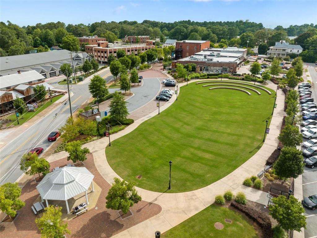 Aerial view of lush oval park with gazebo, trees, and brick buildings in Wehunt Meadows community, Hoschton, Georgia