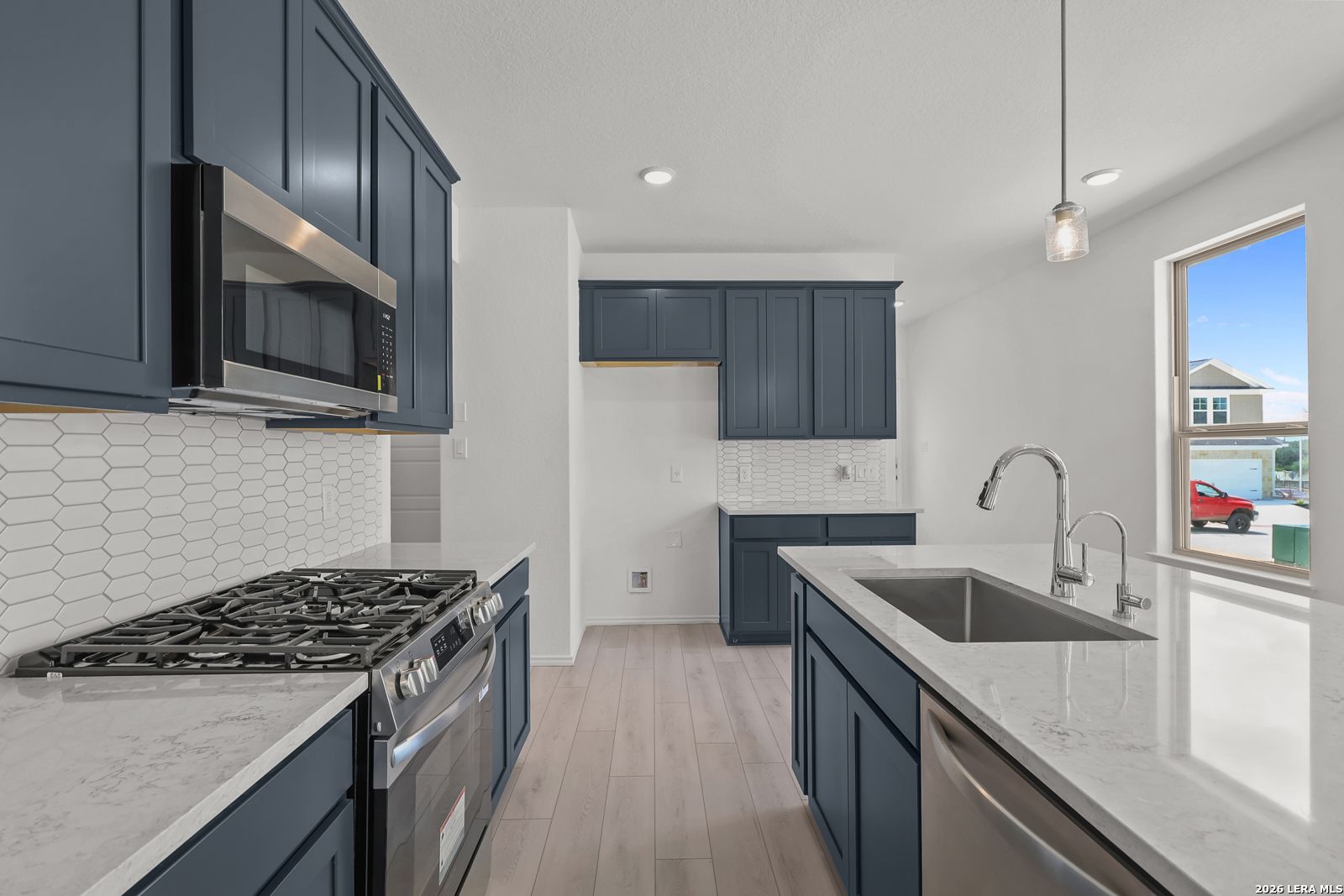 Modern kitchen with navy cabinets, quartz countertops, and stainless appliances in The Gillian C home, San Antonio, Texas.