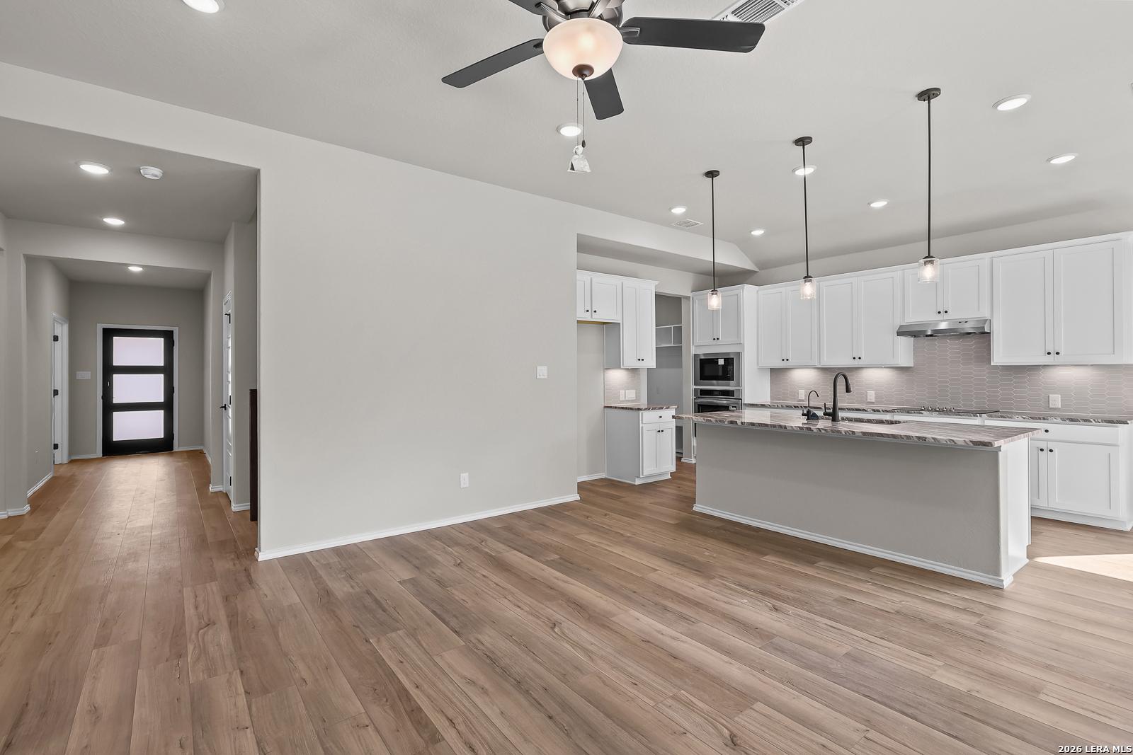 Open-concept kitchen with white cabinetry, pendant lights, and large island in Davidson Homes Sequoia C floor plan, Royal Crest San Antonio