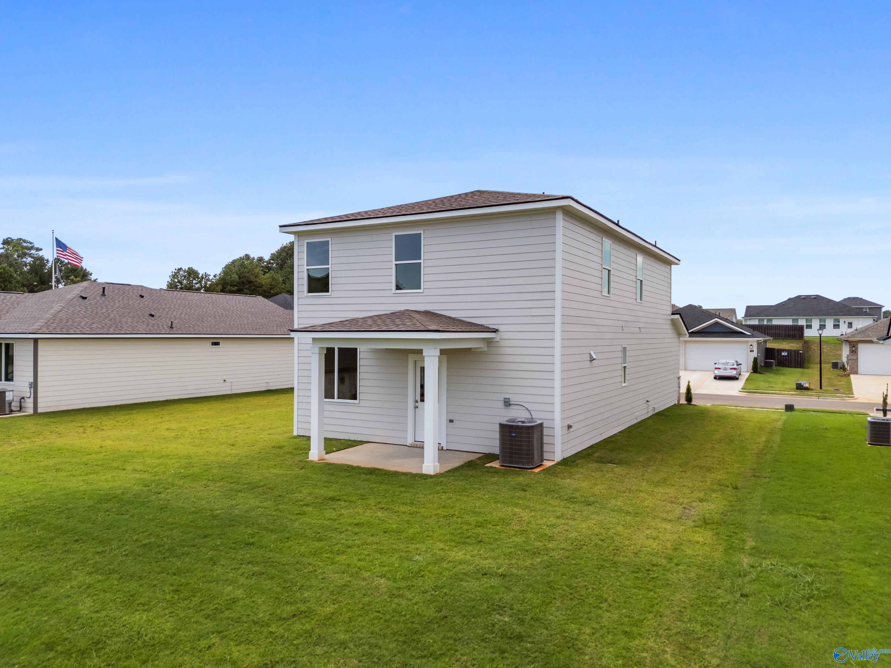 Two-story beige home with covered front porch, two-car garage, and lush green lawn in Evergreen Mill, Madison, Alabama - Davidson Homes The Augusta