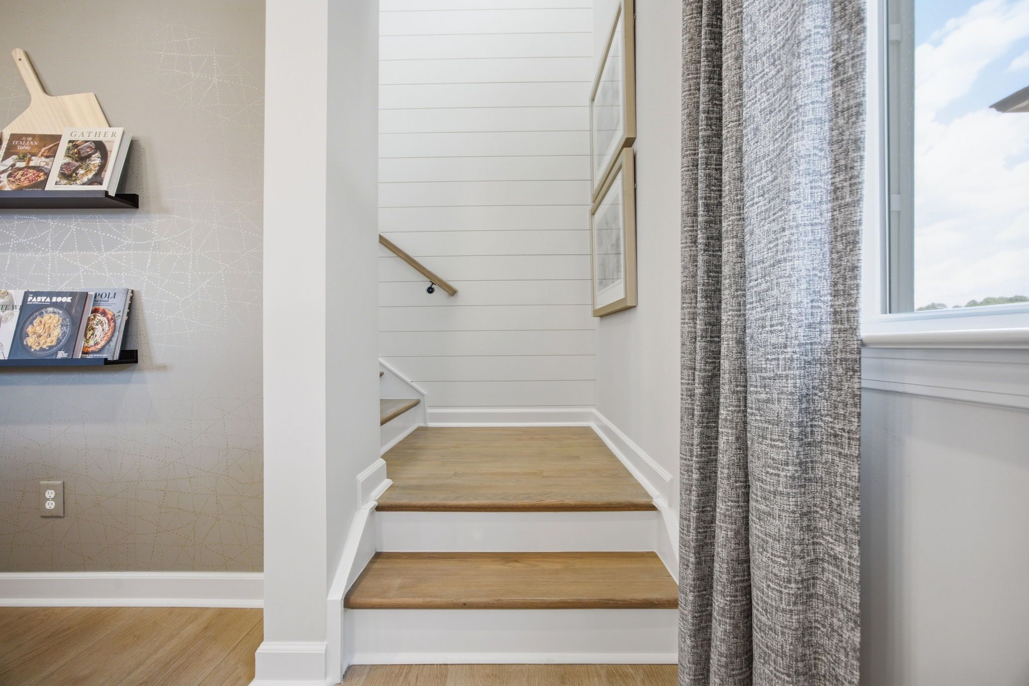 Staircase with wood treads and shiplap wall at Forestville Yard in Knightdale, NC by Davidson Homes with decorative shelving.