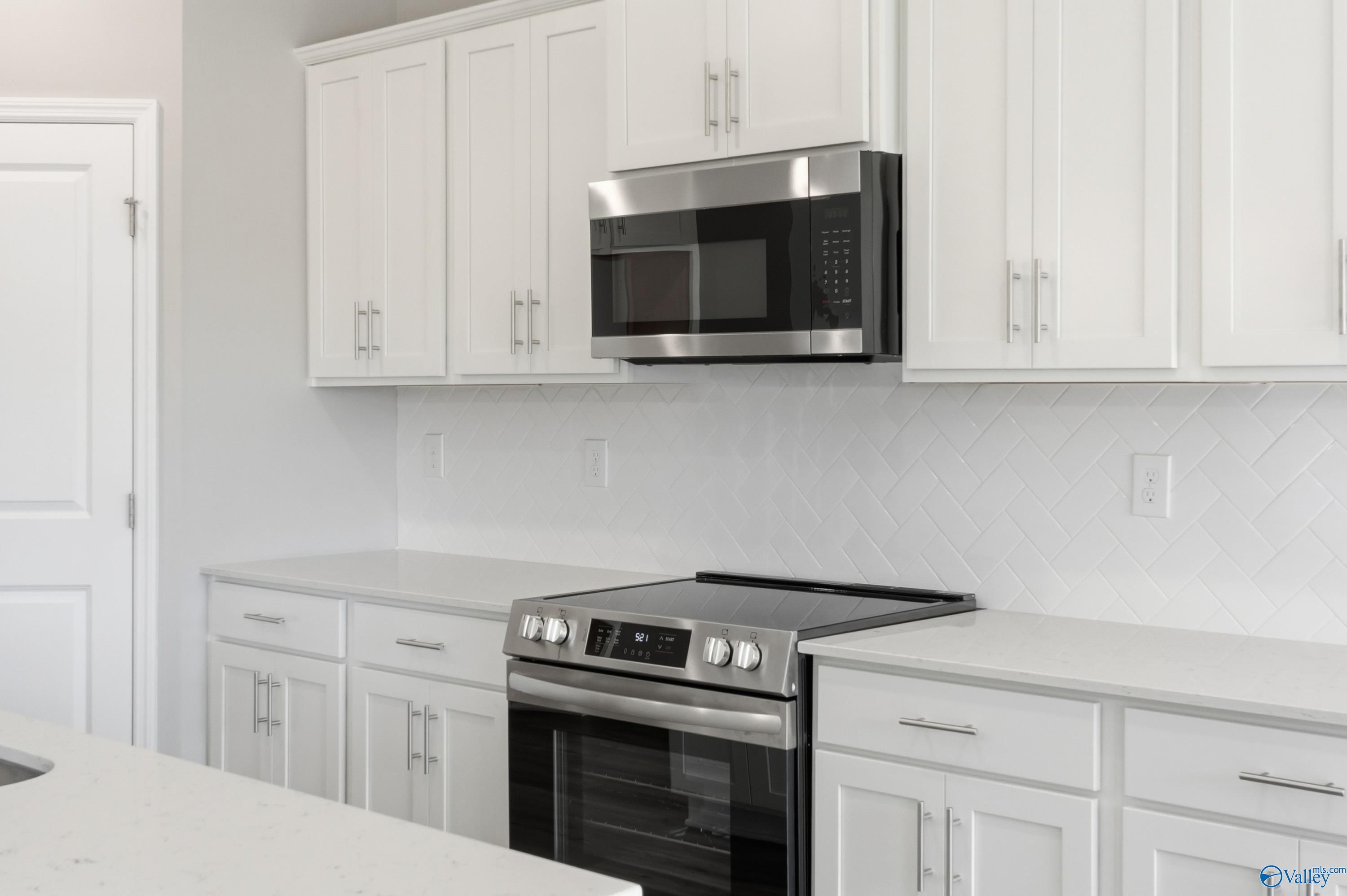 Modern white kitchen with stainless steel appliances, subway tile backsplash in Davidson Homes The Rockford, Harvest, AL