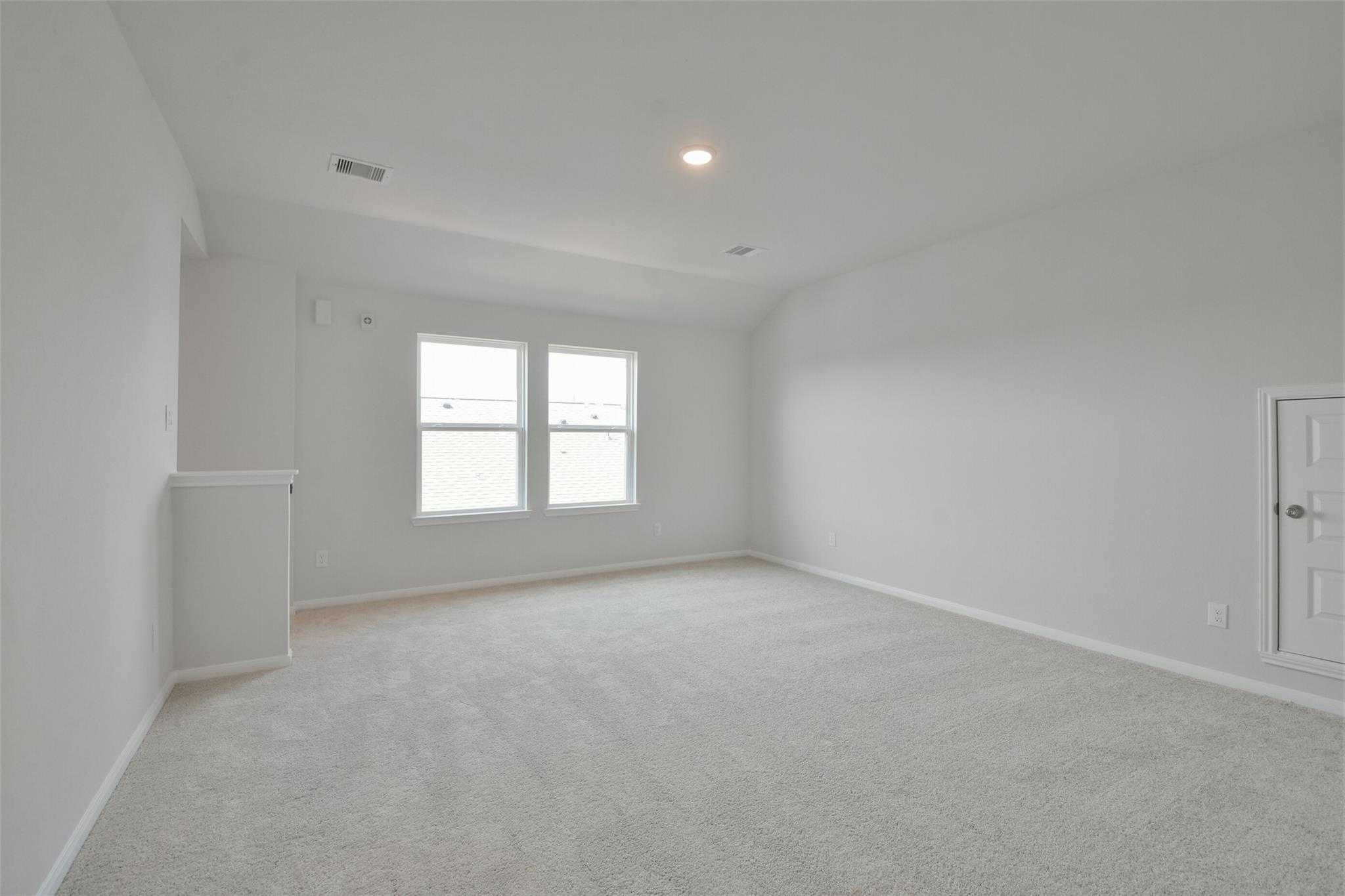 Bright upstairs bedroom with vaulted ceiling, double windows, beige carpet, and closet in Davidson Homes The Tierra A, Dayton, Texas