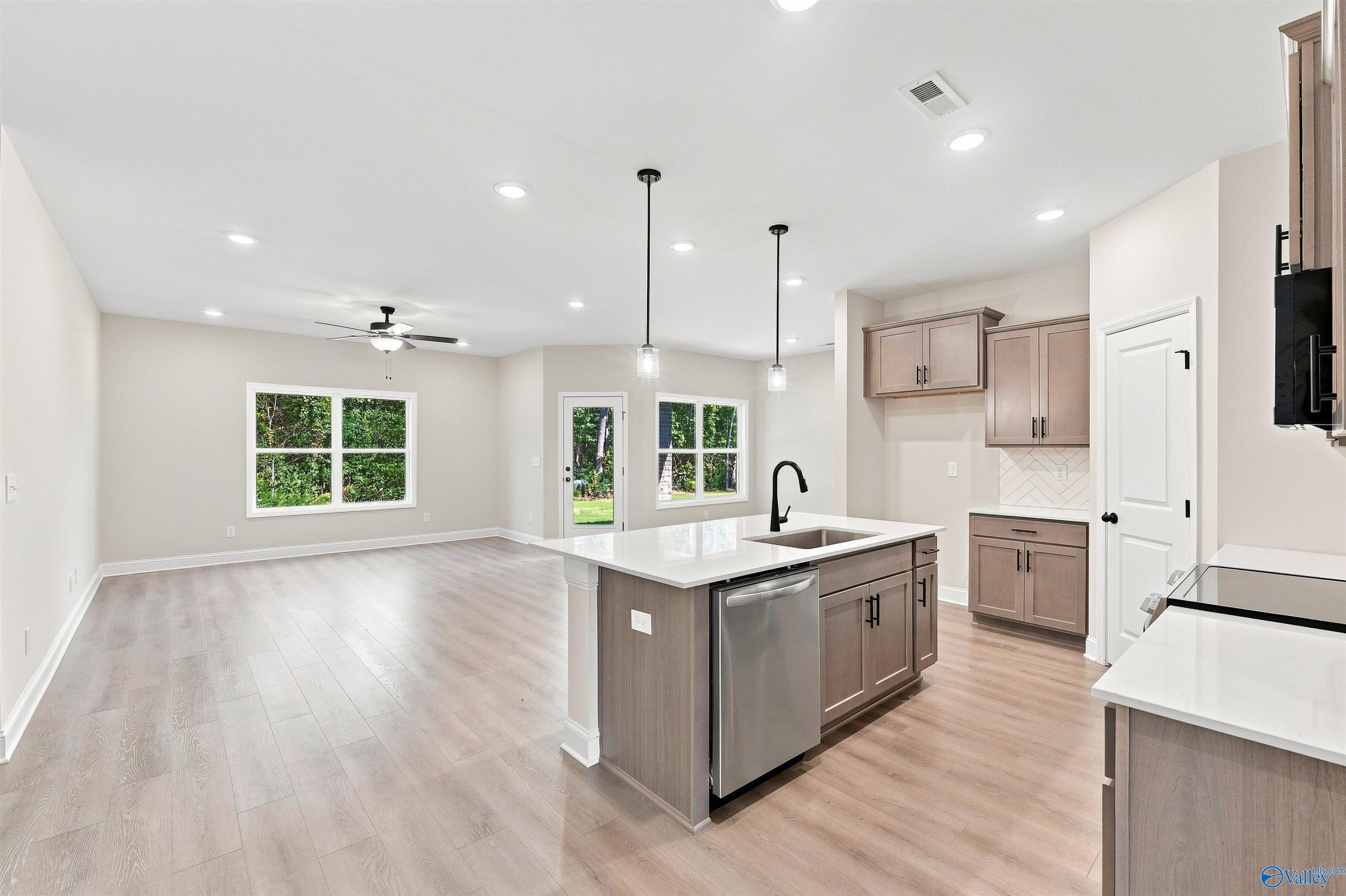 Open-concept kitchen with island and light wood flooring in The Daphne floor plan at Spragins Cove, Huntsville, Alabama.