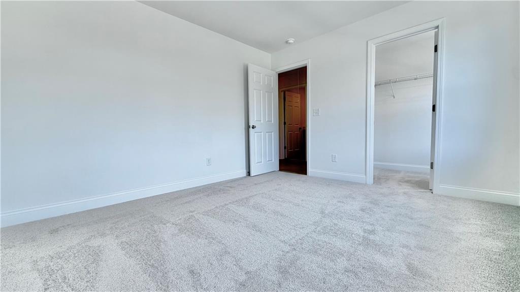 Spacious bedroom with carpeted floor and walk-in closet in The Hickory C floor plan at Wehunt Meadows, Hoschton, GA.