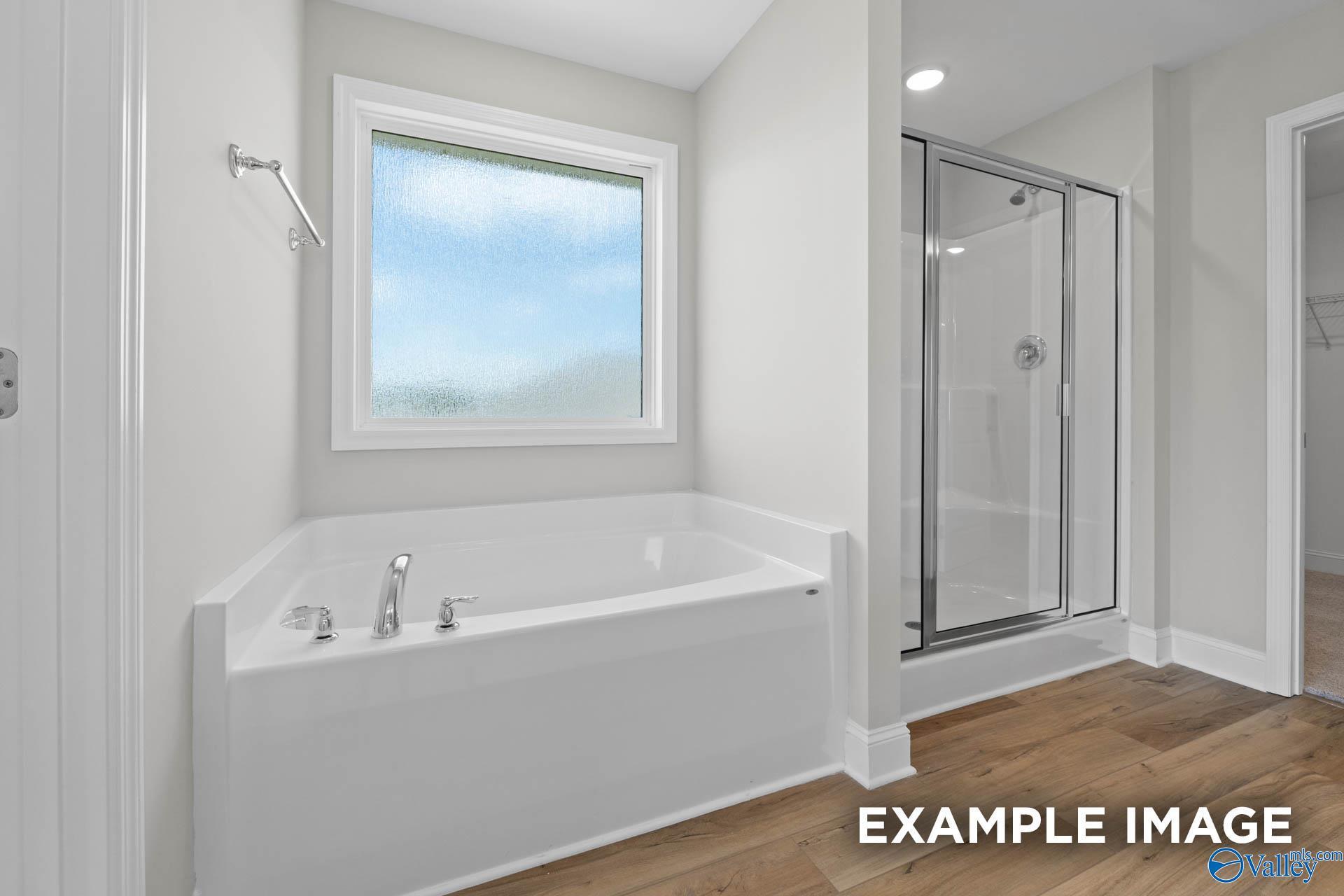 Elegant master bathroom with corner soaking tub, glass walk-in shower, and large window in Davidson Homes The Chelsea A, Athens, Alabama