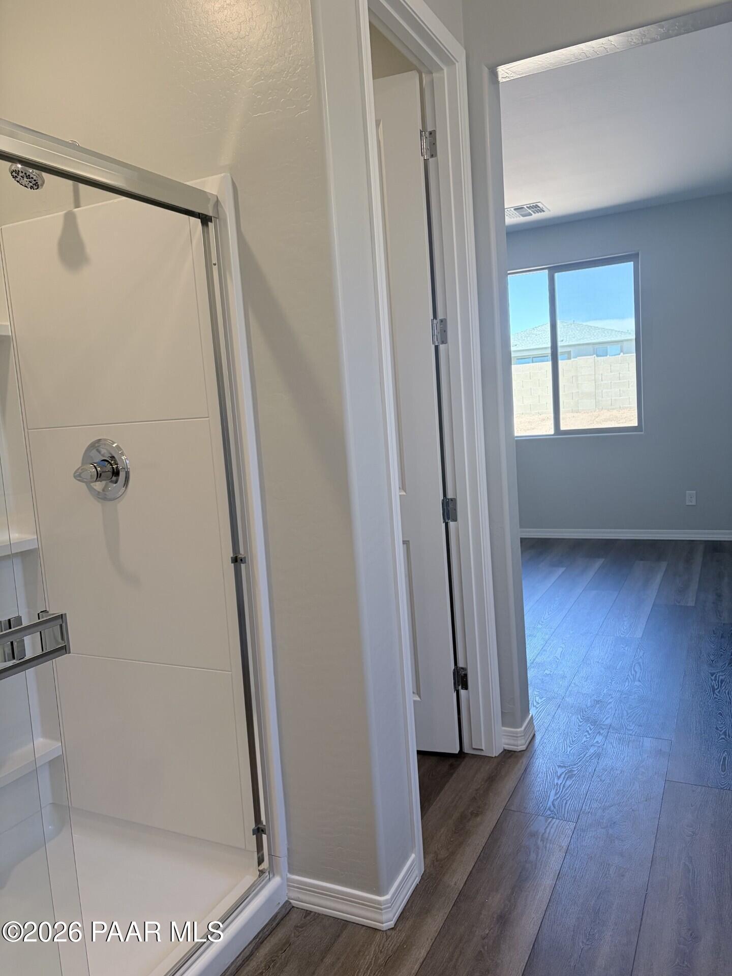 Modern shower and bright bedroom with wood-look flooring in The Frontier A home at North Ridge, Prescott Valley, Arizona.