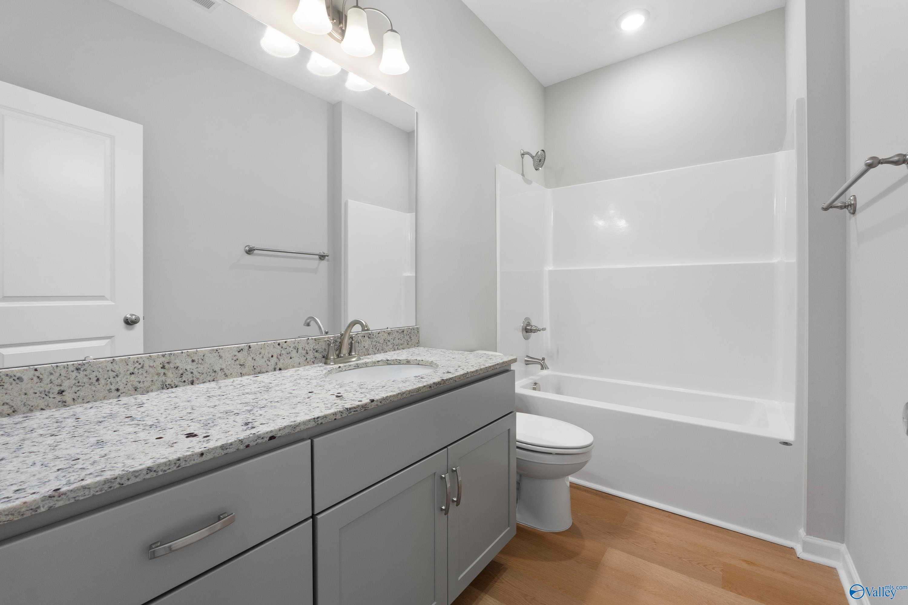 Modern bathroom with granite vanity, tub-shower combo, and gray walls in Davidson Homes The Orion, Athens, Alabama