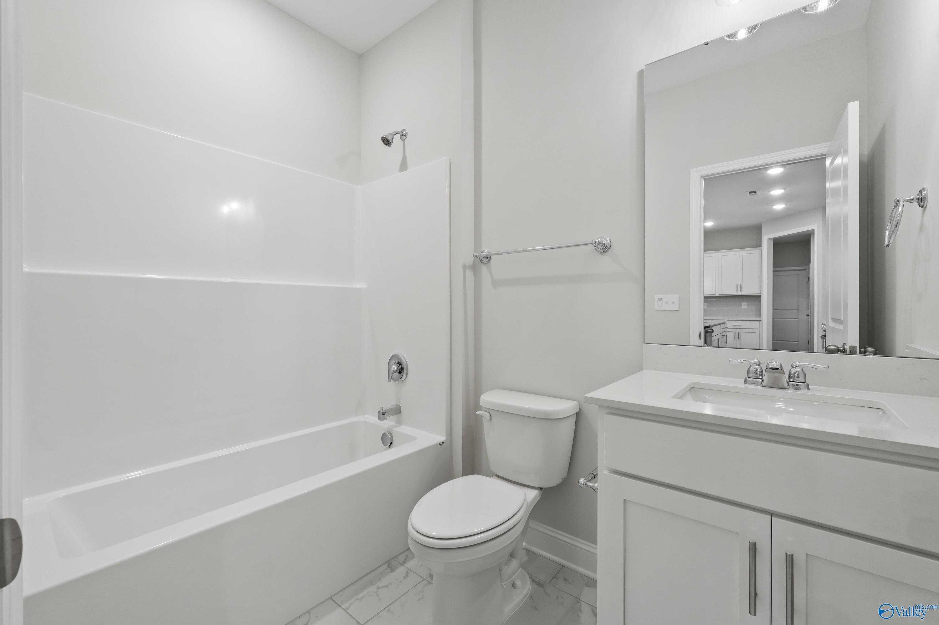 Bright white full bathroom with separate tub, glass shower, single vanity, and toilet in Davidson Homes The Lanier, Creekside, Harvest, Alabama