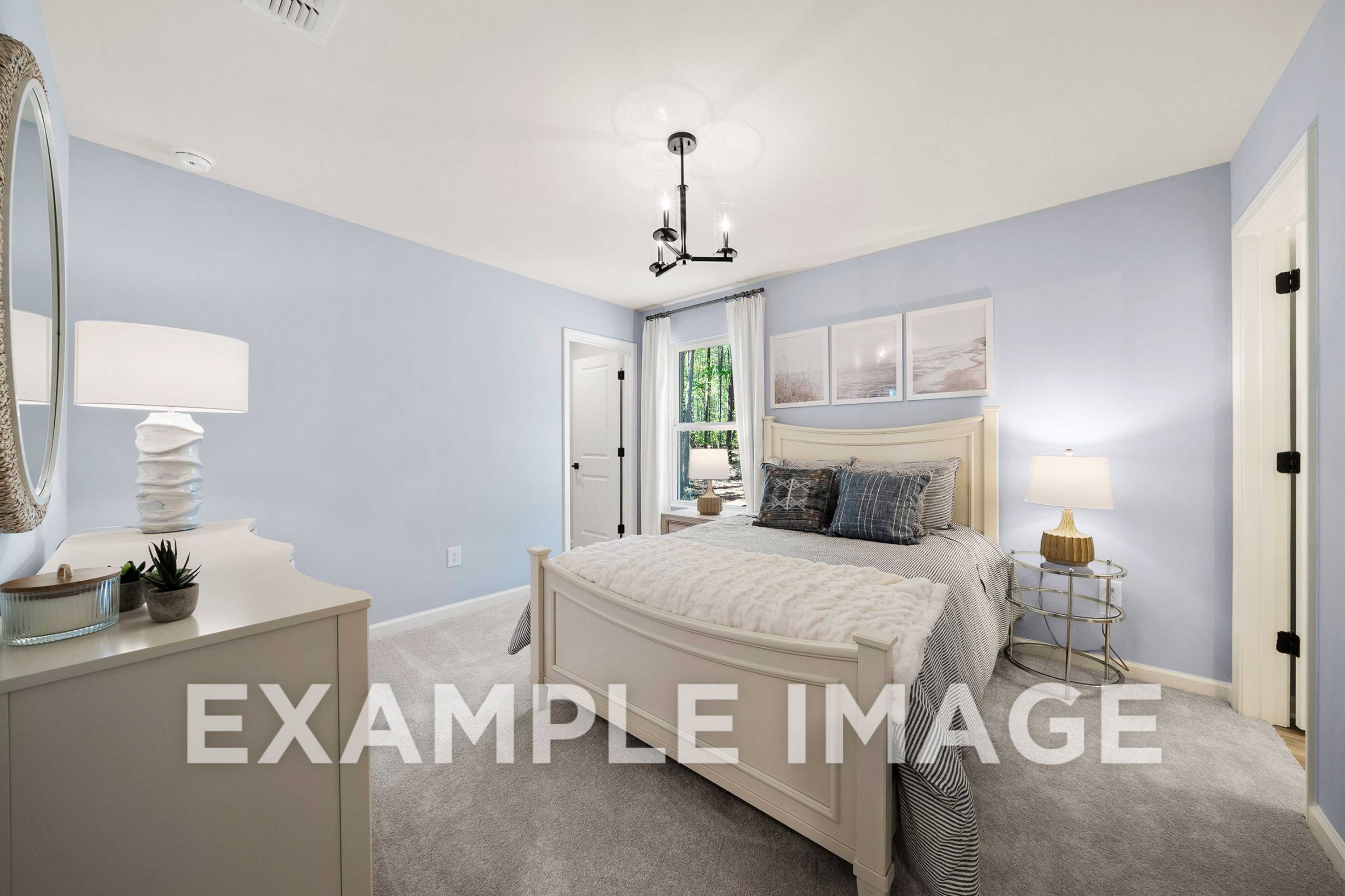 Spacious master suite in The Hickory A, light blue walls, white upholstered king bed, chandelier, large windows, modern decor