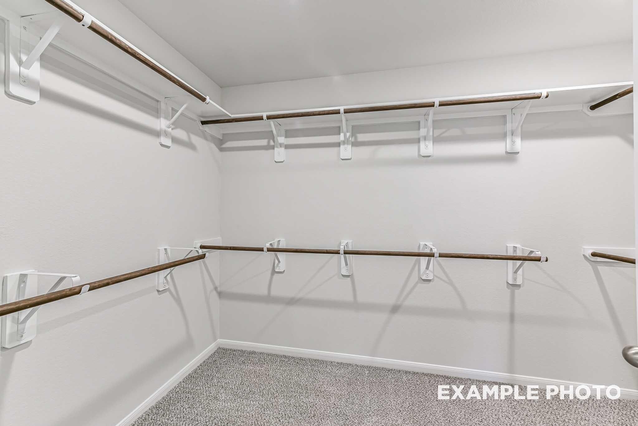 Spacious walk-in closet with wooden shelves and hanging rods in master suite, Davidson Homes The Riviera A, Rosharon, Texas