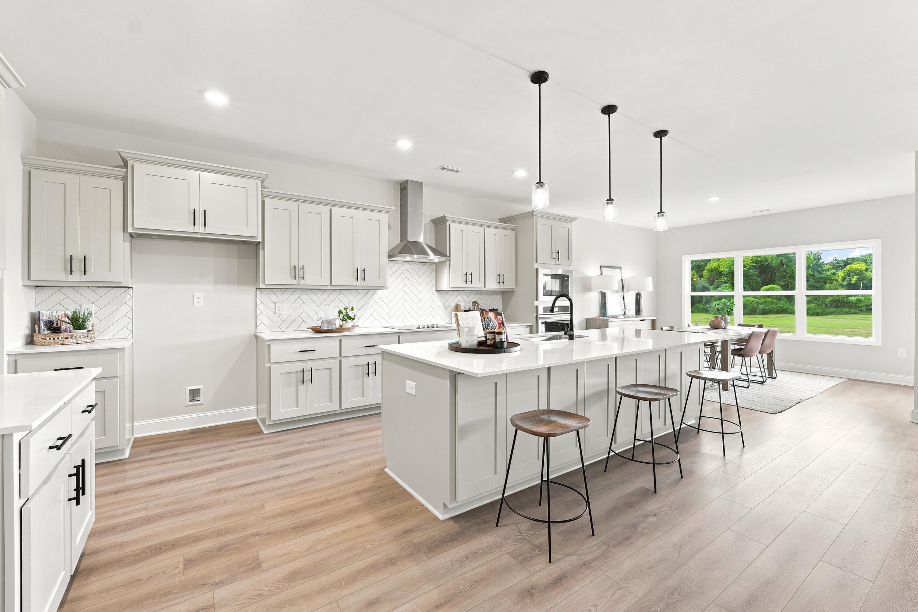 Modern kitchen with white cabinets and large island at Riverton Preserve in Huntsville, AL, built by Davidson Homes.