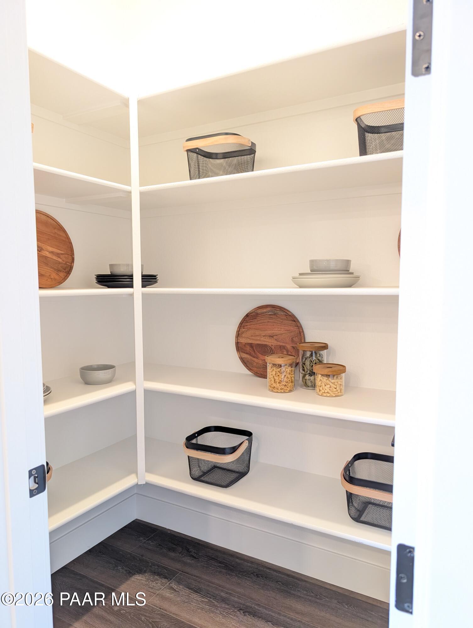 Organized walk-in kitchen pantry with white shelving in The Boulder II H floor plan at South Ranch, Prescott, Arizona.