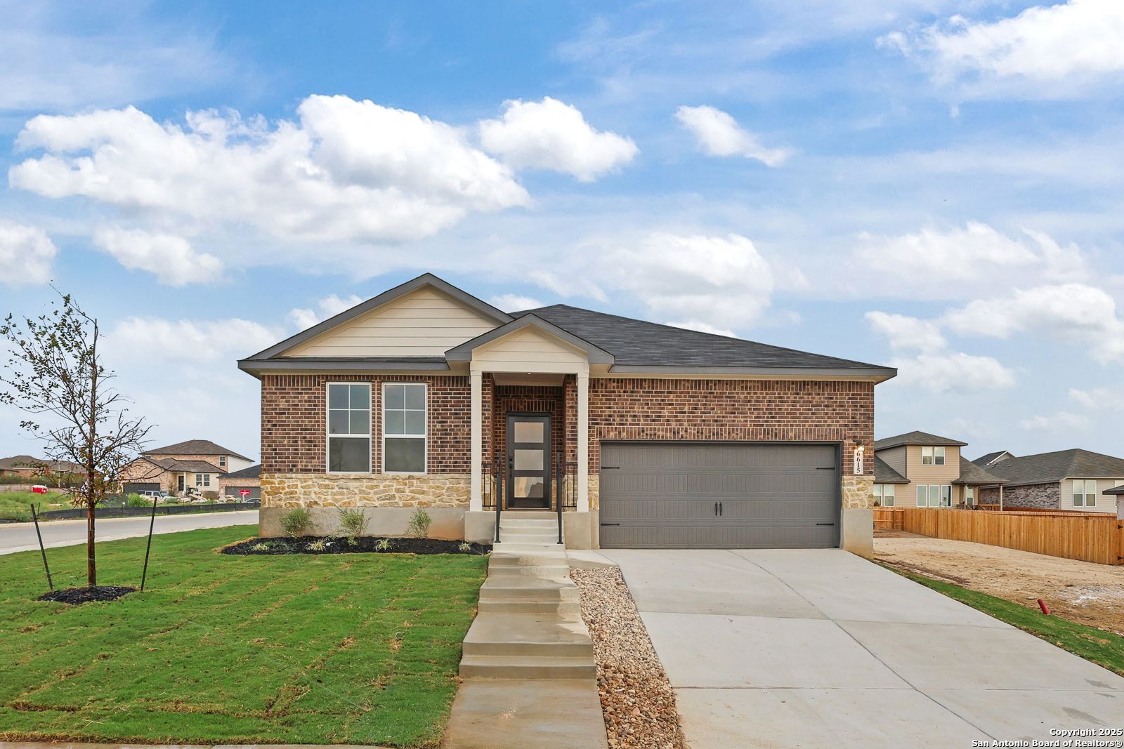 Modern 1-story brick home with stone accents, 2-car garage, and landscaped yard in Comanche Ridge, San Antonio, Texas - Davidson Homes The Daphne K
