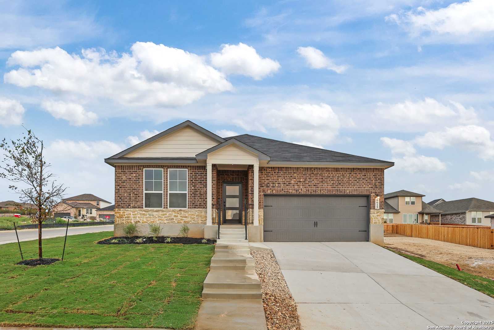 Modern 1-story brick home with stone accents, 2-car garage, and landscaped yard in Comanche Ridge, San Antonio, Texas - Davidson Homes The Daphne K