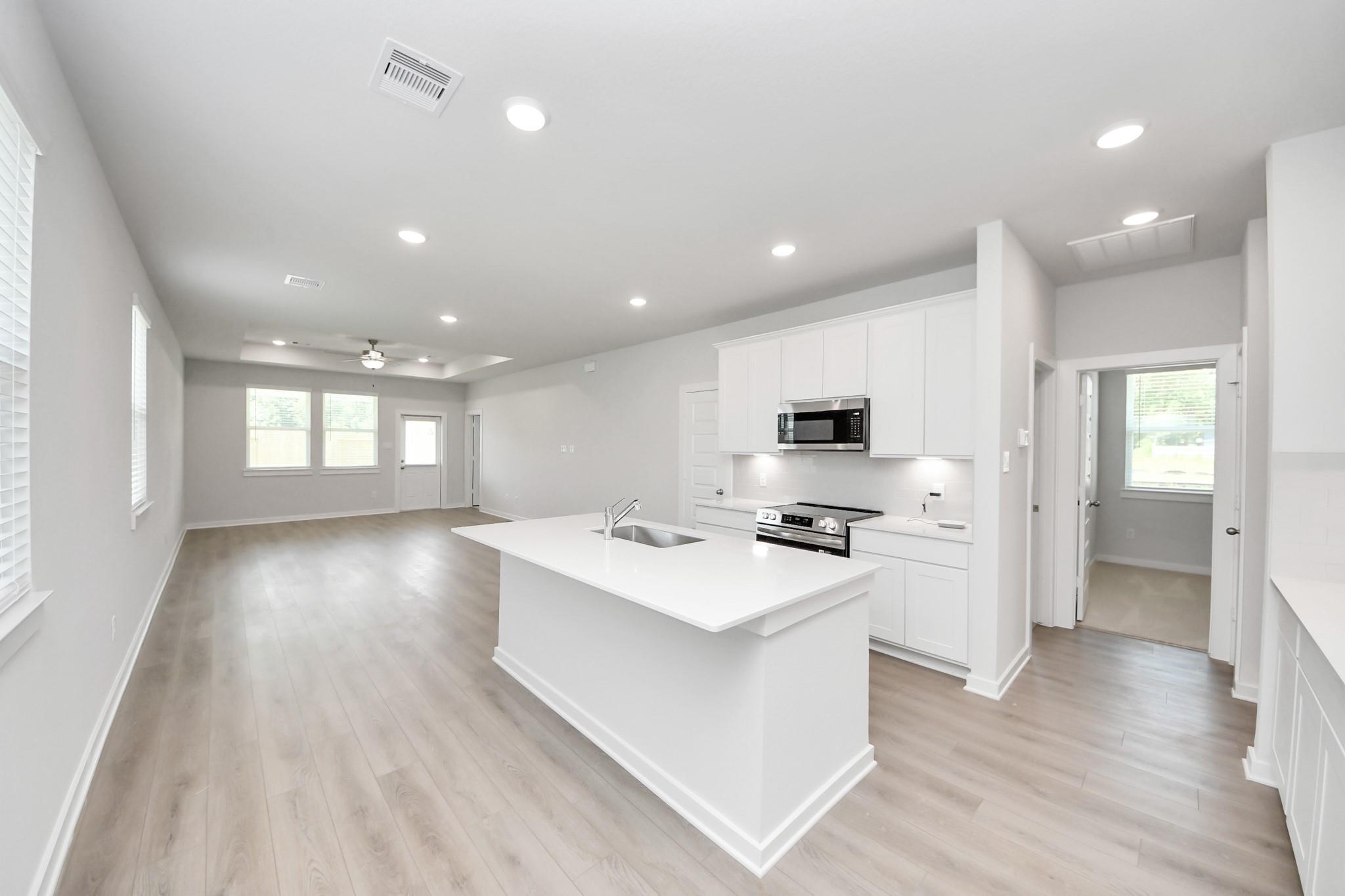 Modern open-concept kitchen with white cabinets and island in The Frio F floor plan at Liberty Estates, Cleveland, Texas.
