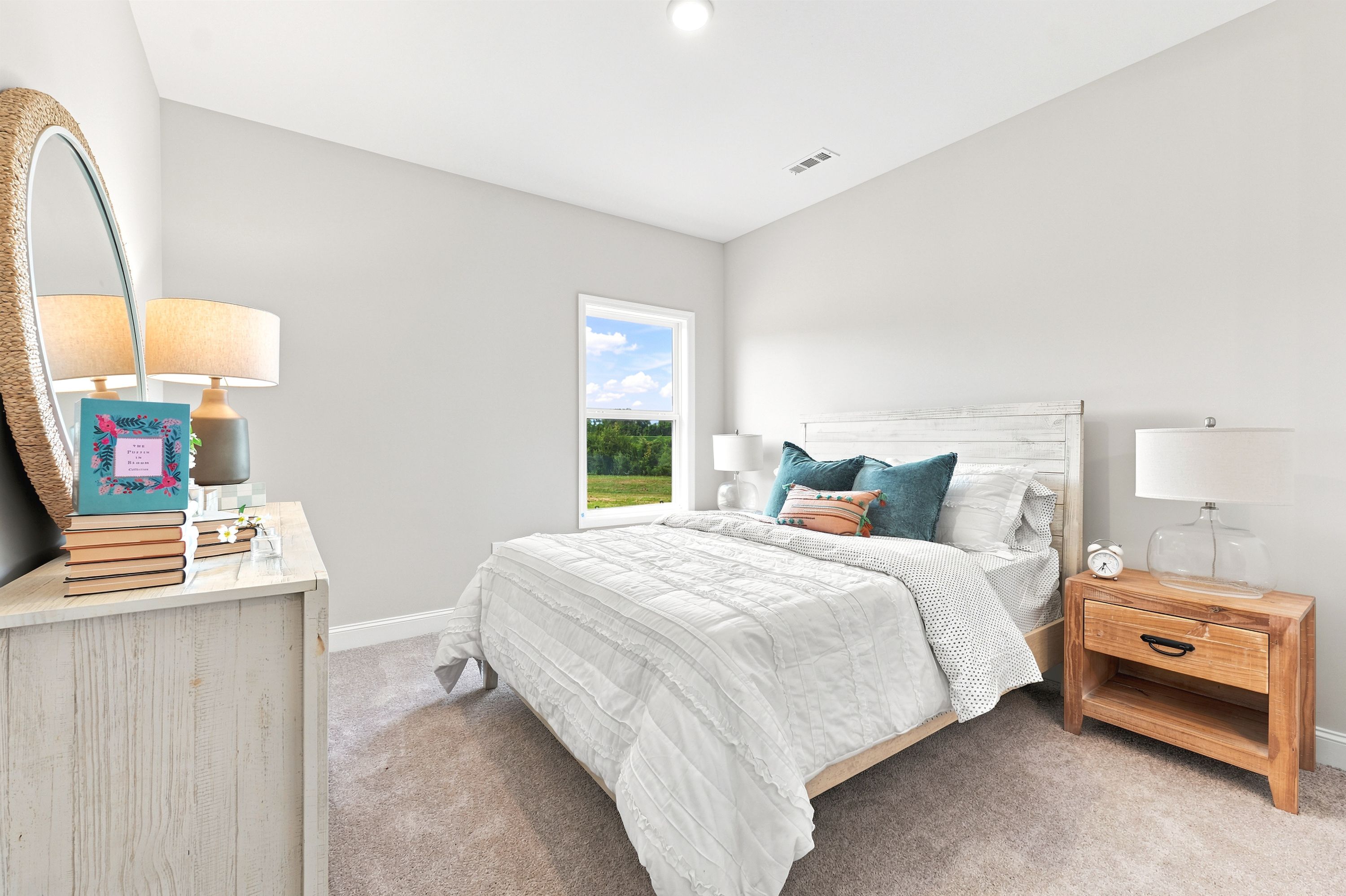 Bright, cozy bedroom at Riverton Preserve in Huntsville, AL by Davidson Homes featuring a rustic wood bed and nightstand.
