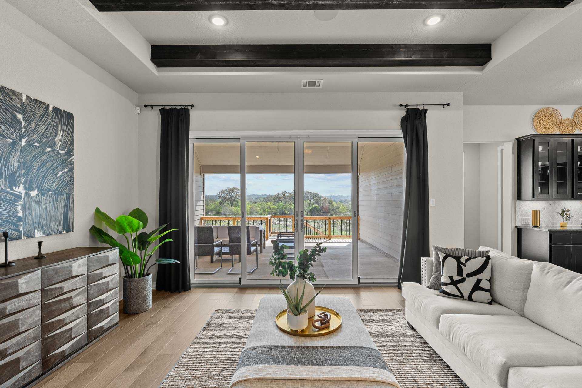 Spacious living room in The Summerlin B Davidson Homes design with sliding doors to wooded patio view, white sofa, hardwood floors, modern decor