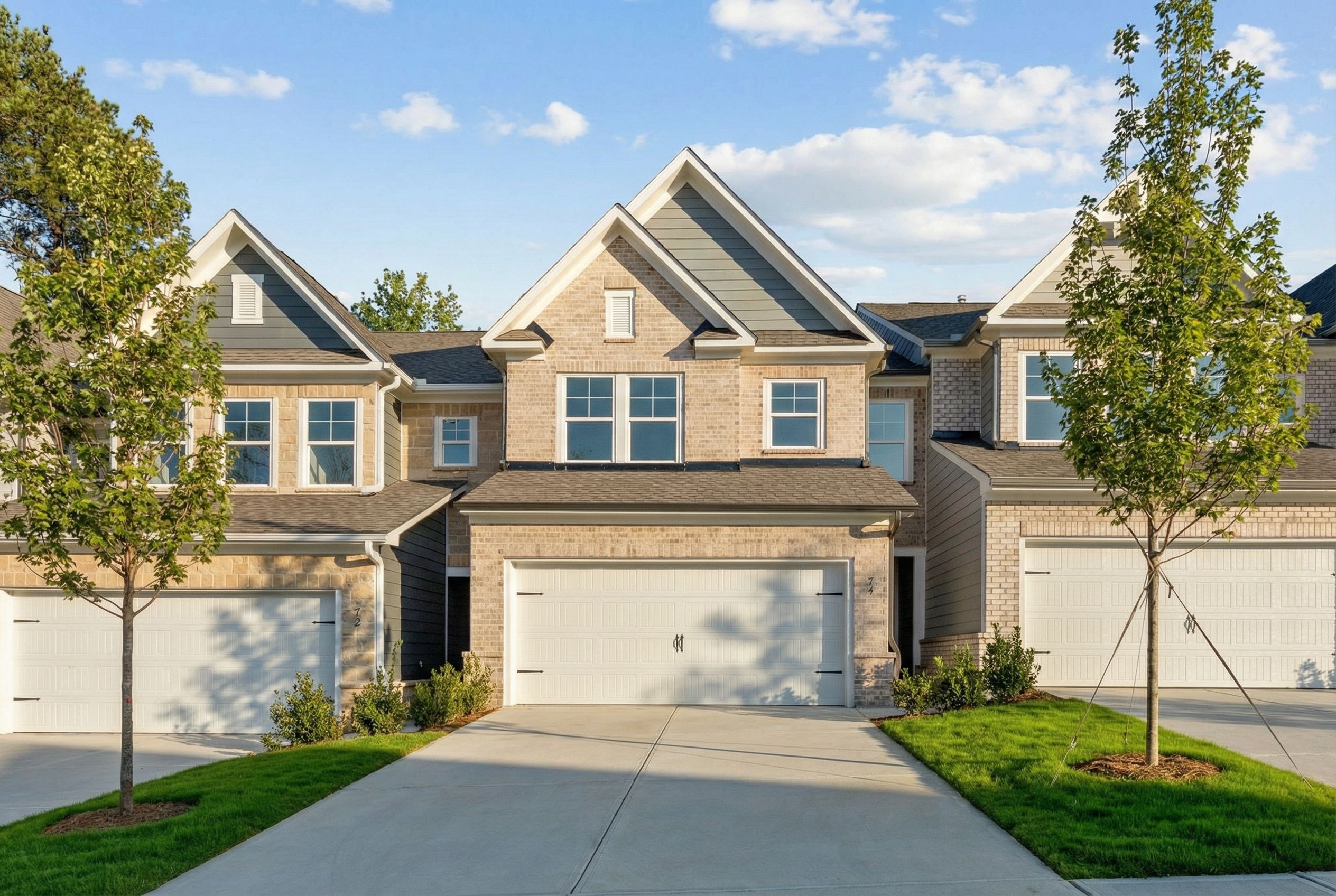 Row of modern 2-story townhomes with brick facades, gray siding, 2-car garages in Lake Shore, Winder, Georgia by Davidson Homes
