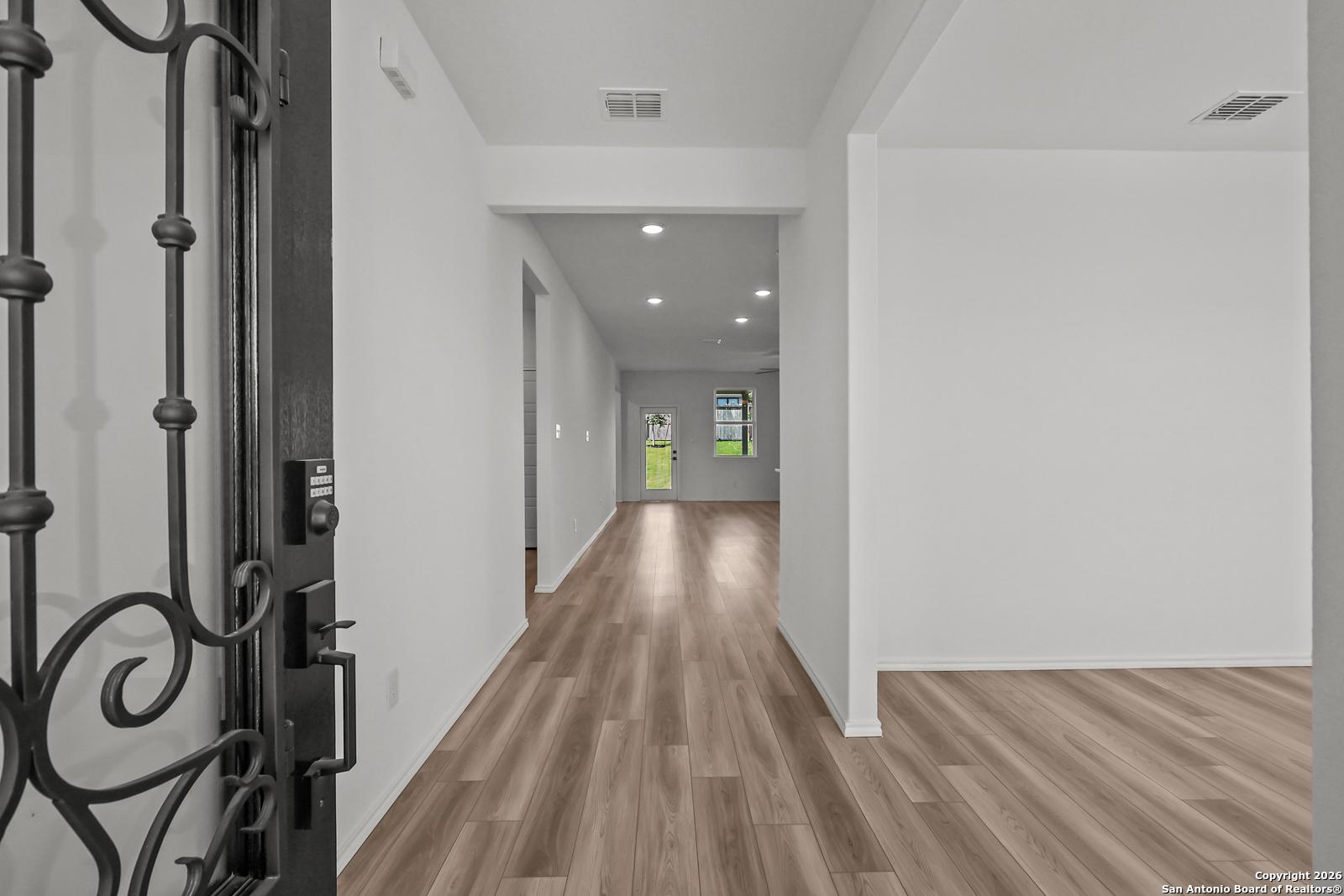 Elegant entry foyer with wrought iron door, luxury vinyl plank flooring, and recessed lighting in Davidson Homes The Douglas E, San Antonio