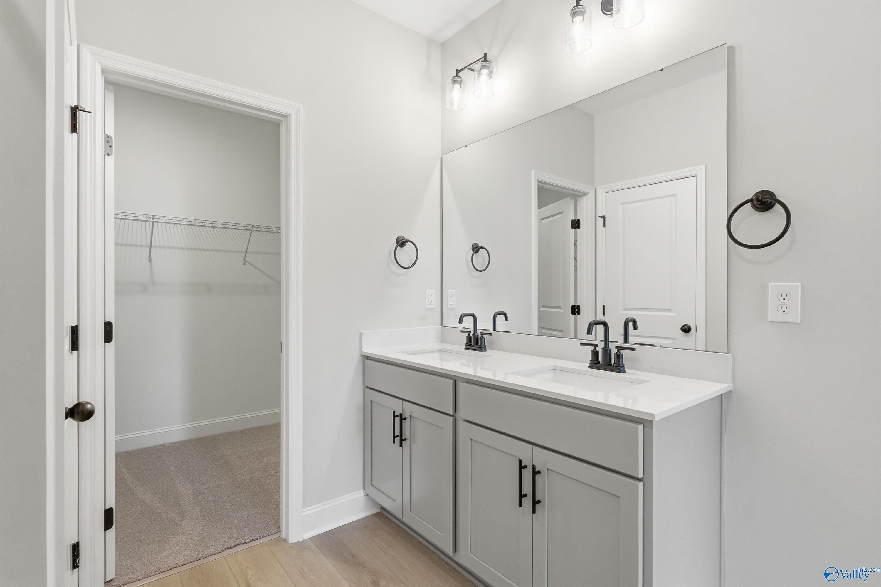 Modern master bathroom with double vanity, gray cabinets, dual sinks, and closet access in Davidson Homes The Franklin C, New Market, Alabama