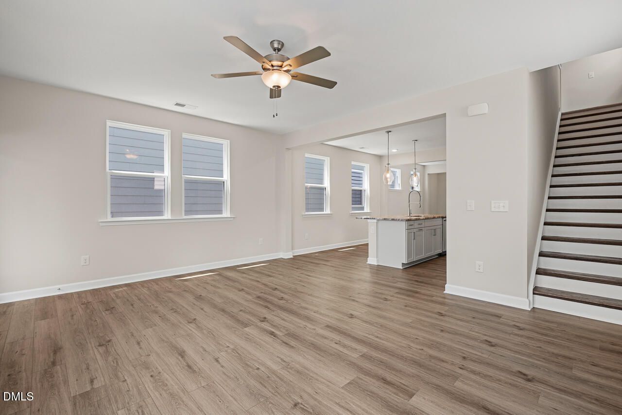 Open-concept living room and kitchen with wood-look flooring in The Alexander C plan at Forestville Yard, Knightdale, NC.