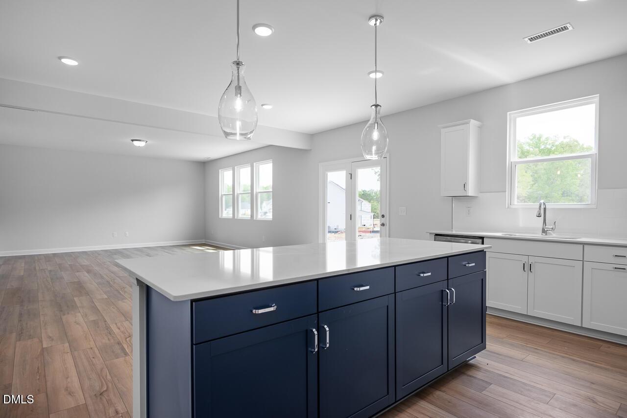 Modern kitchen with navy island, white quartz counters, stainless sink in The Hickory II B by Davidson Homes, Zebulon NC