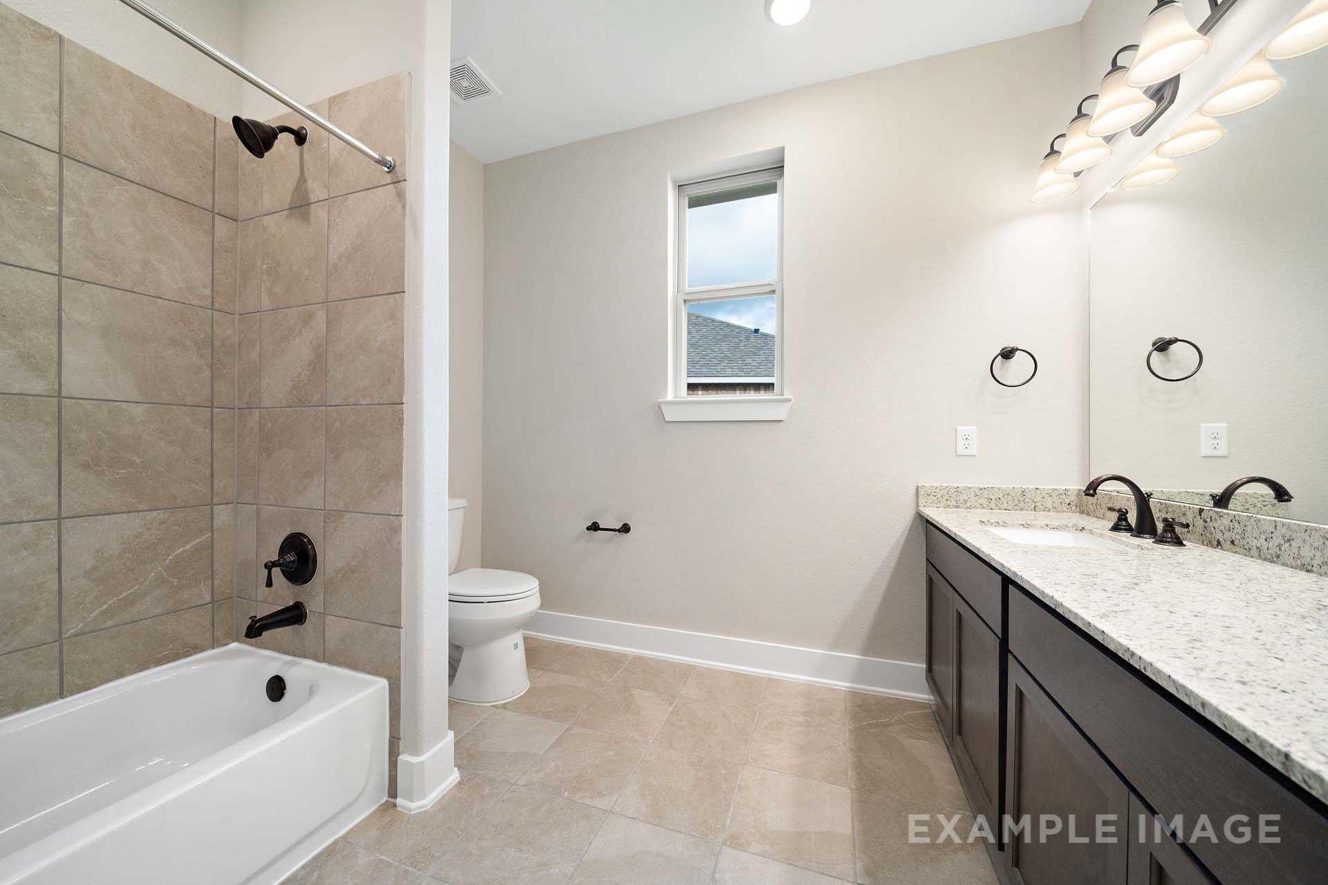 Spacious master bathroom in The Elizabeth A with double vanity, soaking tub, and tiled accents in Rosharon Texas home