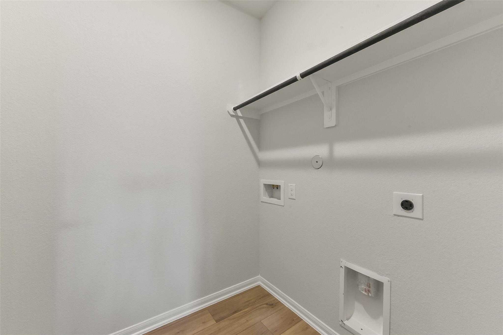 Bright laundry room with hanging rod, washer/dryer hookups, and outlets in Davidson Homes The Laguna B, Magnolia, Texas