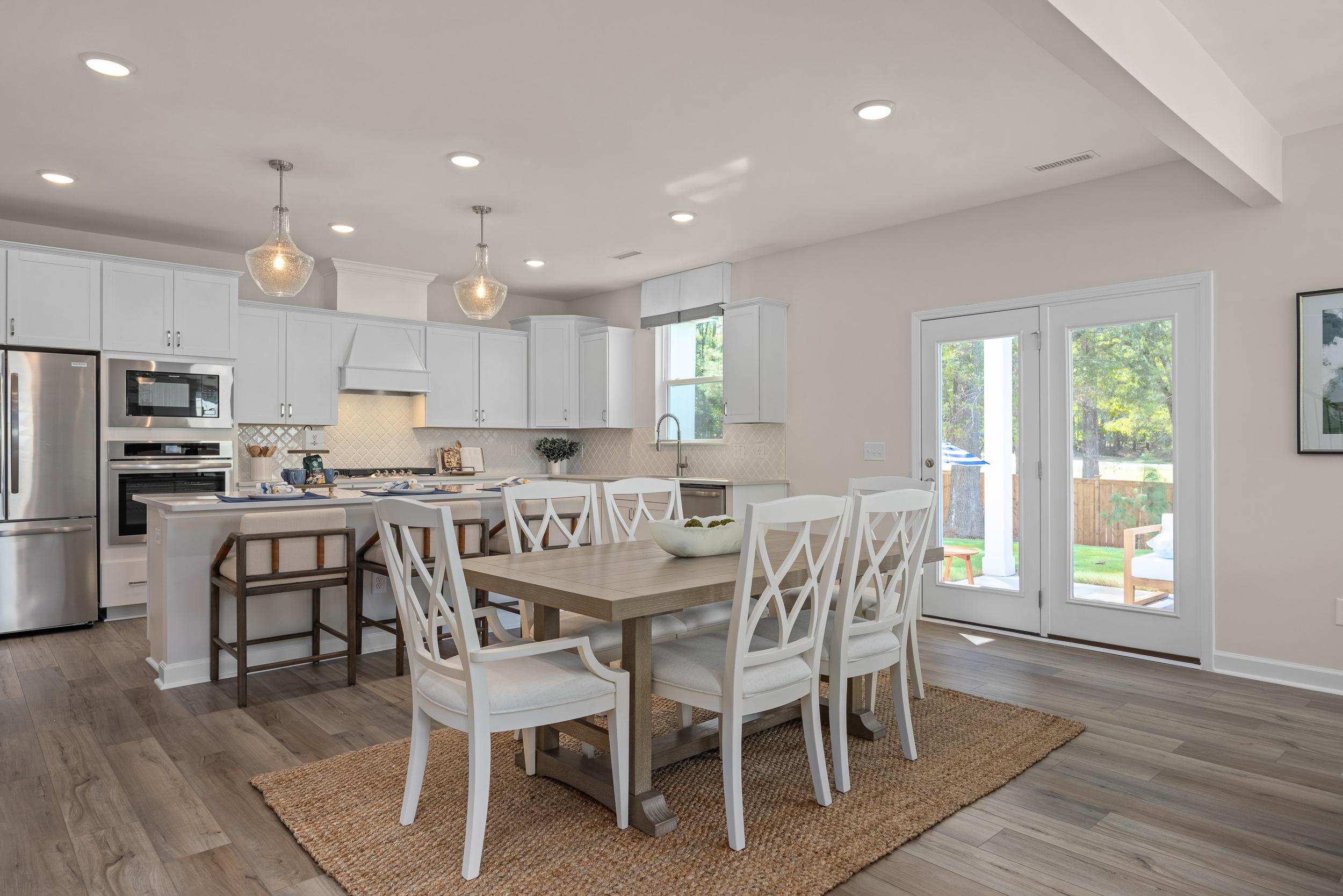 Spacious open-concept kitchen and dining in The Hickory II, white shaker cabinets, large island, farmhouse table, French doors to patio