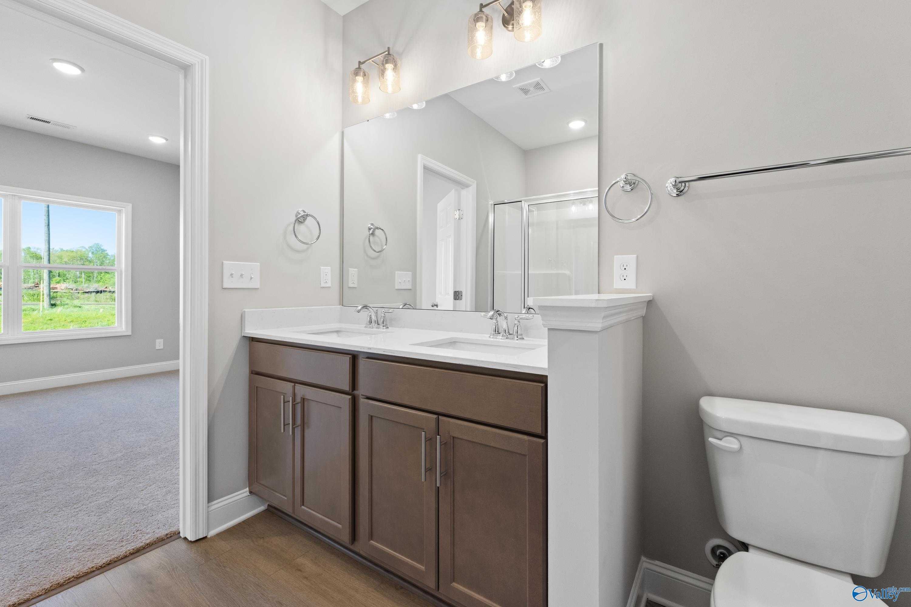 Modern master bathroom featuring double vanity, walk-in shower, and large window in Davidson Homes The Asheville C, Athens, Alabama
