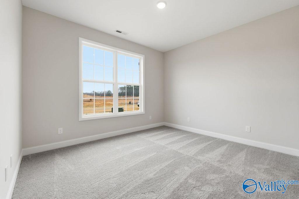 Bright secondary bedroom with large window overlooking rural fields, neutral walls, and gray carpet in Davidson Homes The Rockford B, Hartselle, AL