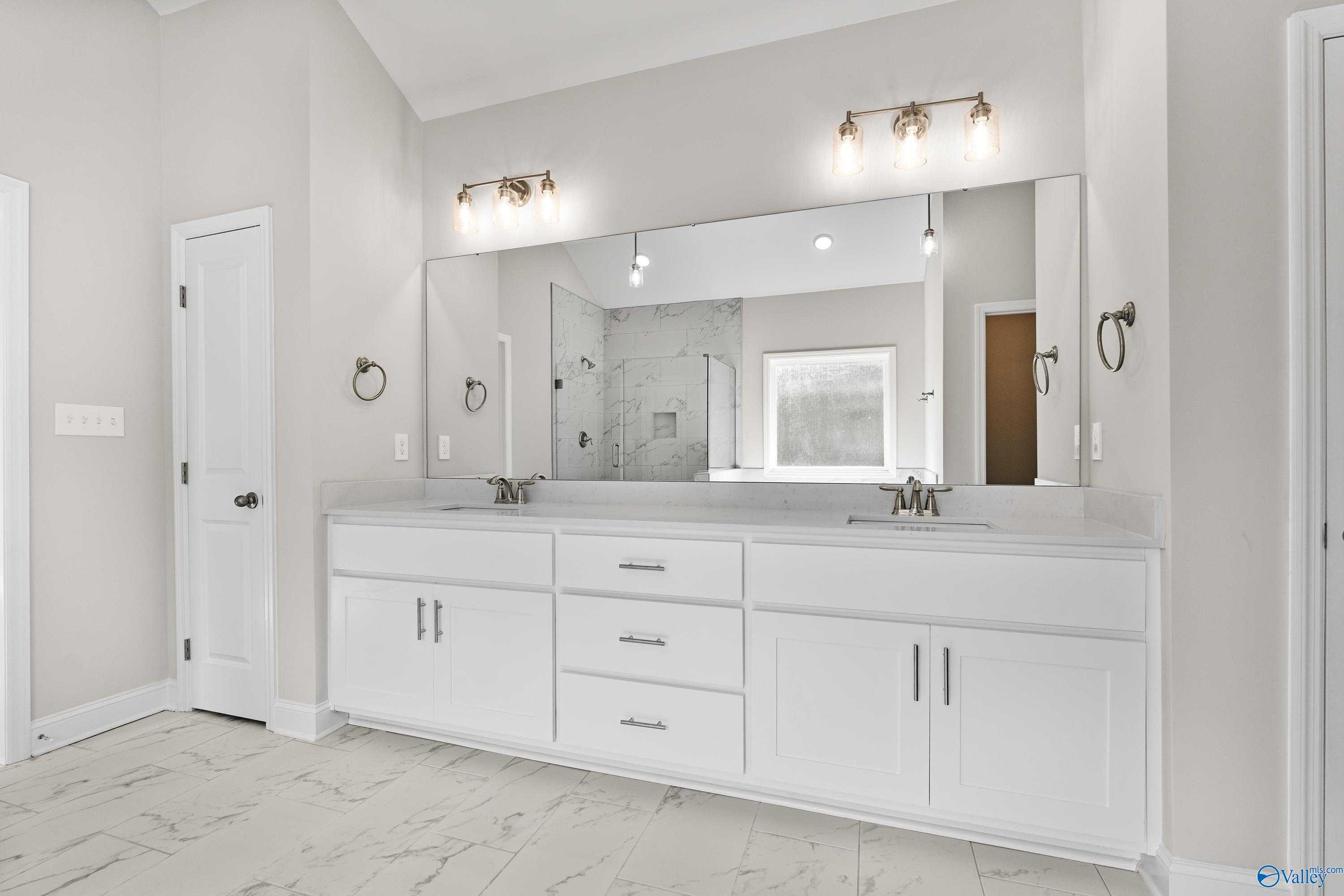 Elegant master bathroom featuring double white vanity, large mirror, and glass shower in Davidson Homes The Finleigh, Toney, Alabama