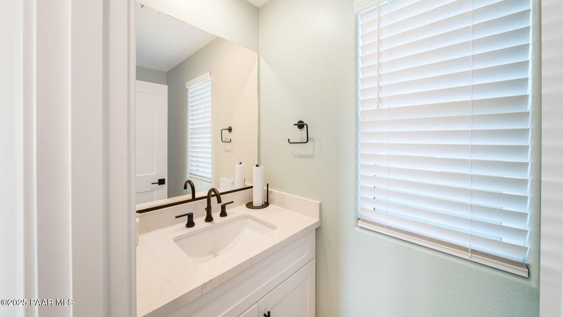 Modern powder room featuring white quartz vanity, bronze faucet, and large mirror in The Wilmington B by Davidson Homes, Prescott, Arizona