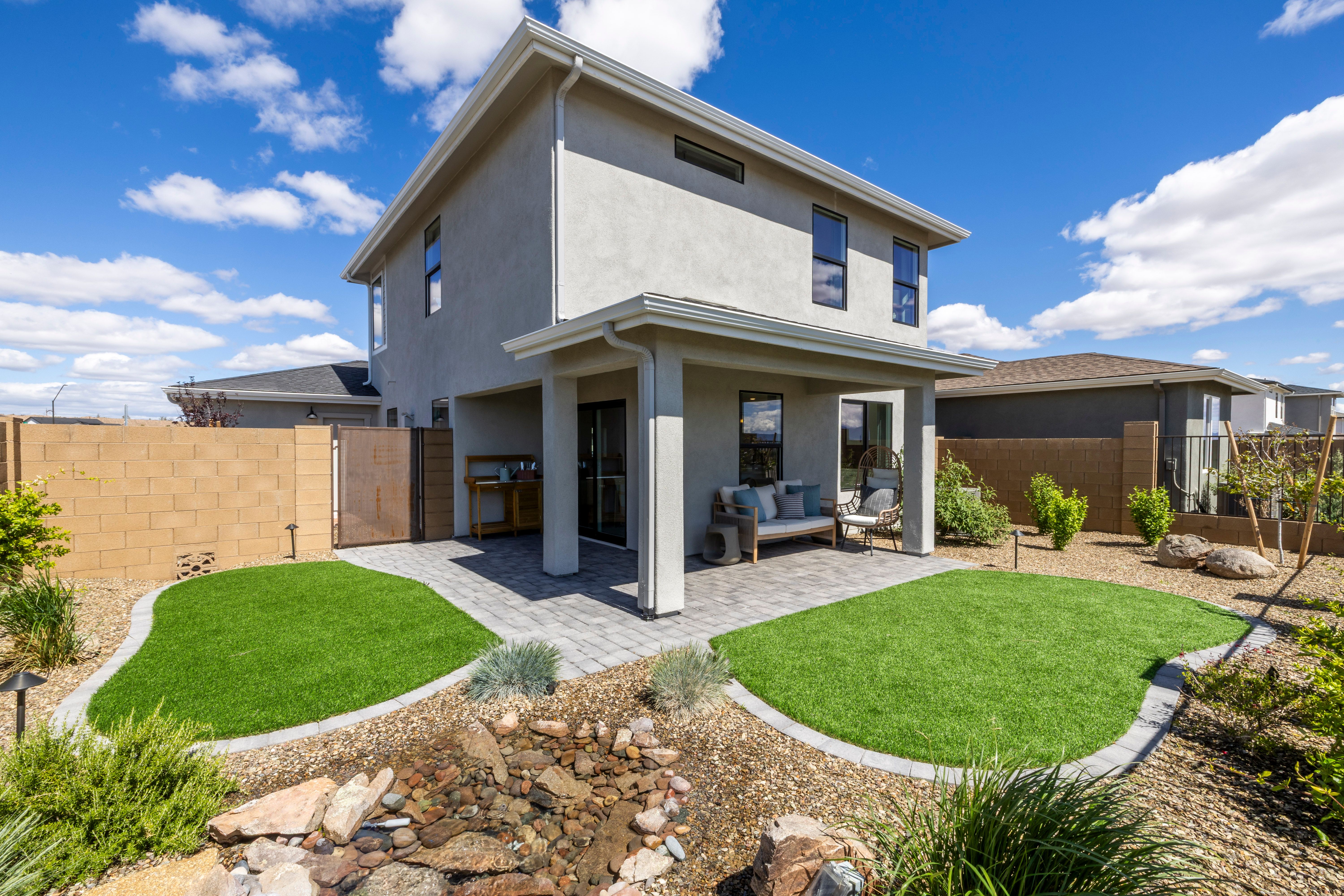 Modern stucco home backyard patio at South Ranch Southern Collection in Prescott Arizona with artificial turf, rock garden, and seating