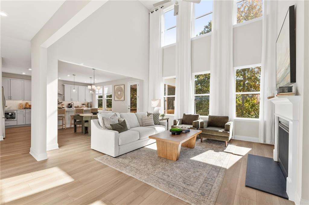 Bright open-concept living room with vaulted ceilings, fireplace, white sofa, and kitchen in The Danbury C, Buford, GA