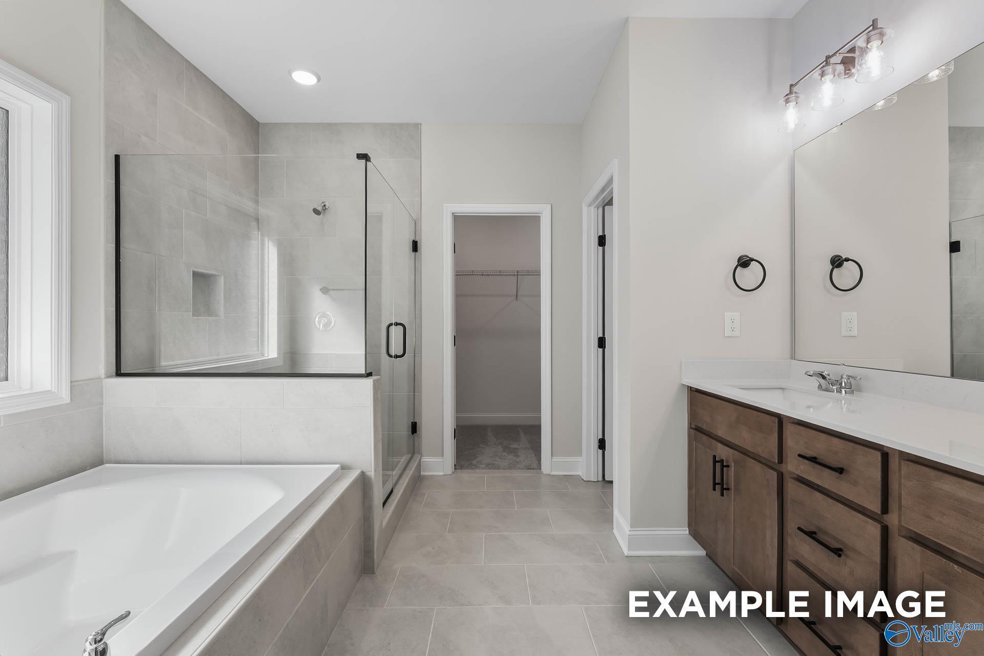 Modern primary bathroom with walk-in shower, soaking tub, and vanity in The Montgomery D floor plan, Anderson Farm, Athens.