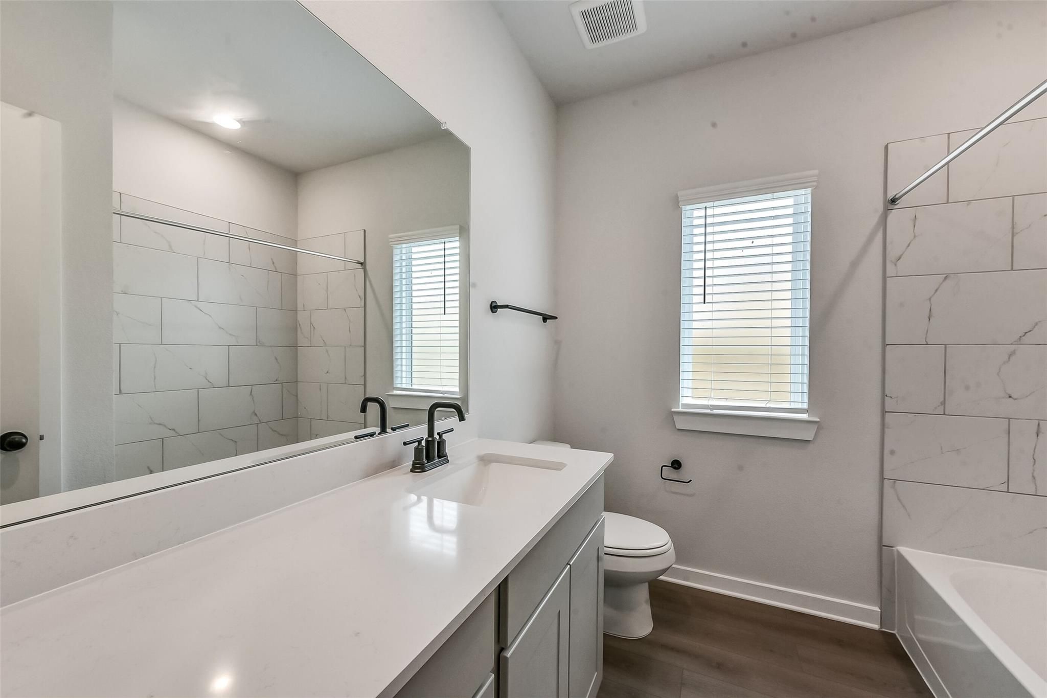 Elegant master bathroom with white quartz double vanity, marble-tile shower, soaking tub in Davidson Homes The Everett C, Crosby Texas