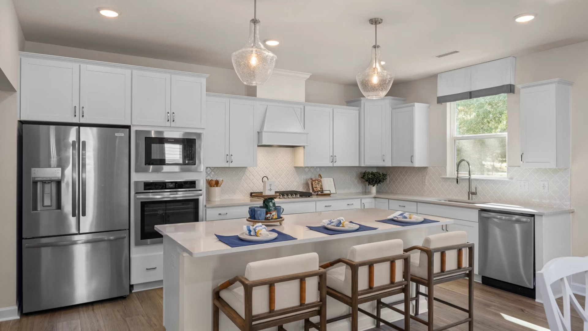 Spacious modern kitchen in Davidson Homes Windgate model home, featuring white shaker cabinets, stainless appliances, quartz island