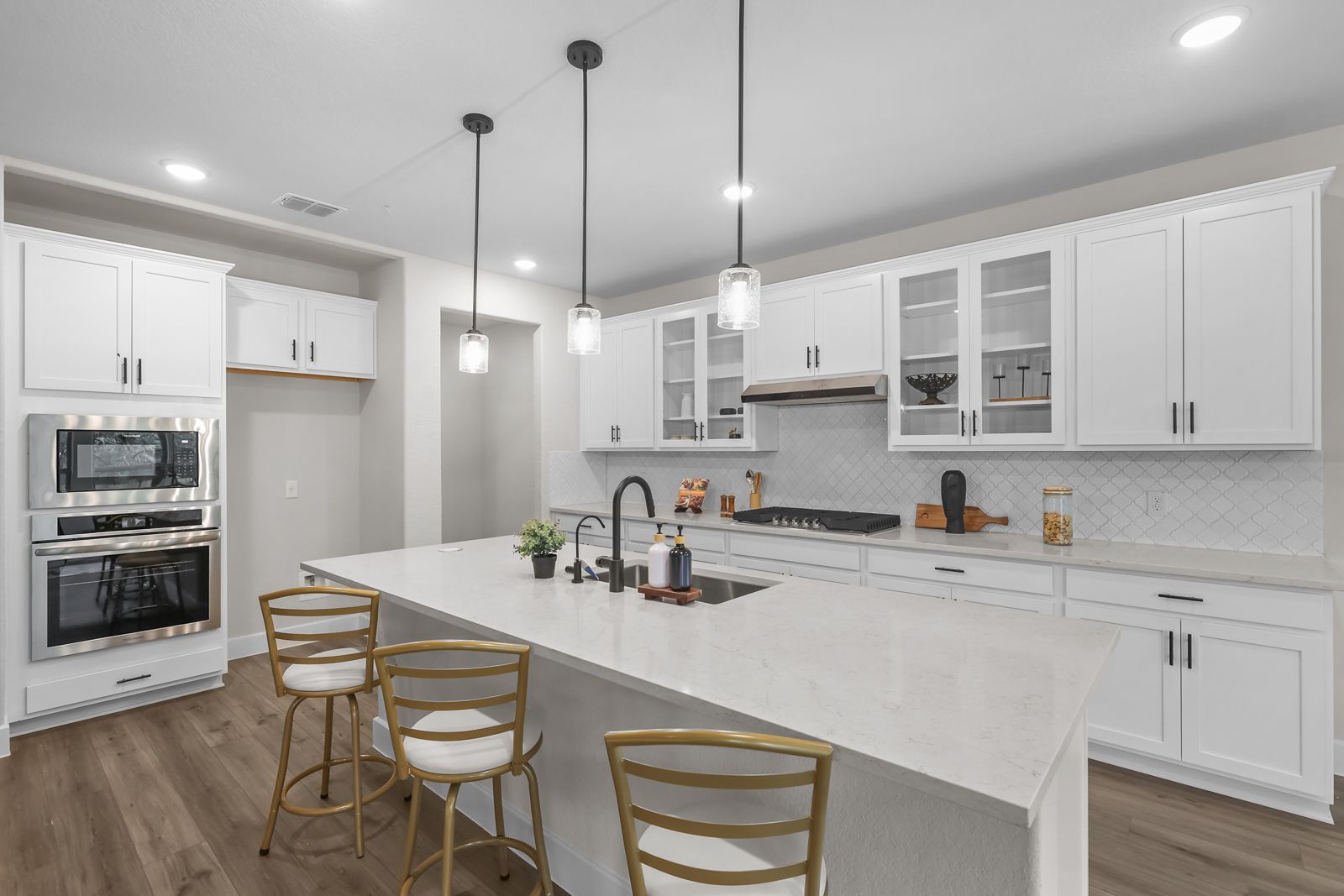 Modern gourmet kitchen in The Belmont featuring white cabinets, a large quartz island, and stainless steel appliances.