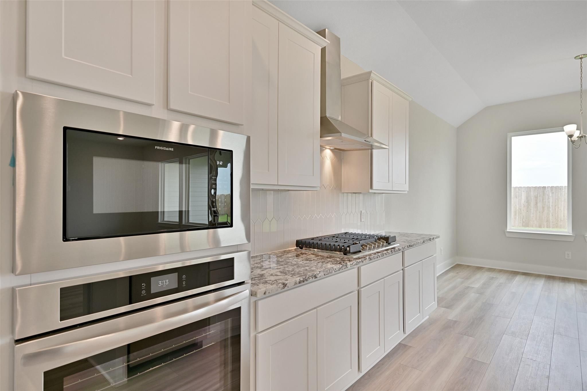 Modern kitchen with white shaker cabinets, stainless double oven, quartz counters in Davidson Homes The Edward A, Lago Mar, Texas City