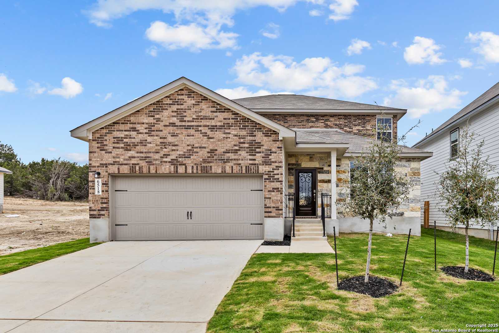 Modern two-story brick home with two-car garage, covered porch, and landscaped front yard in Royal Crest, San Antonio, Texas