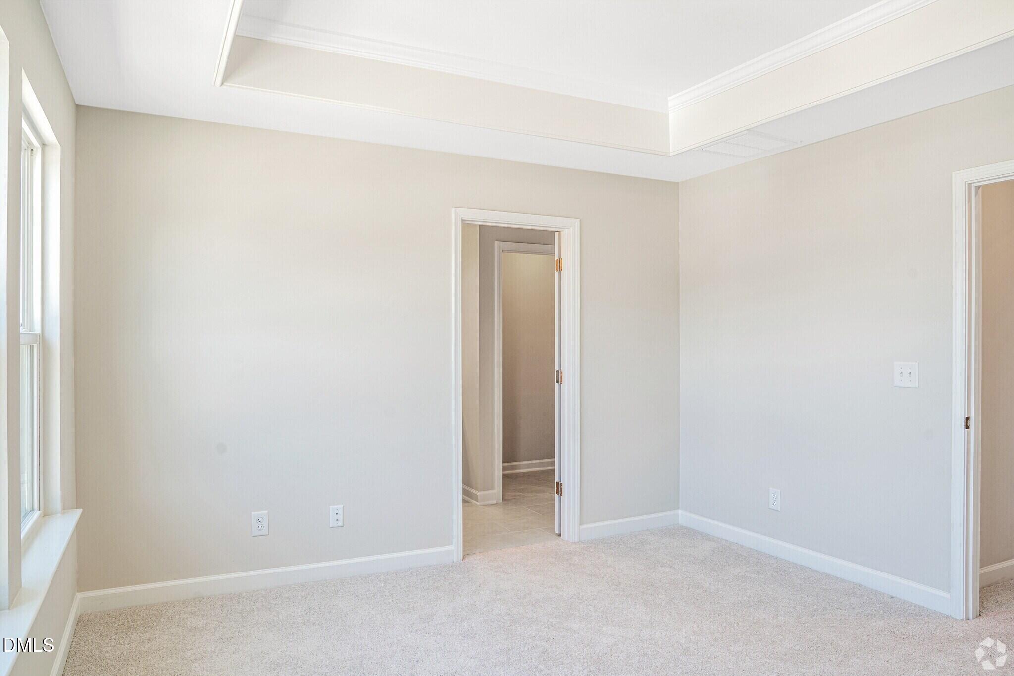 Bright carpeted bedroom with tray ceiling and natural light in Davidson Homes The Mitchell floor plan, Knightdale, NC