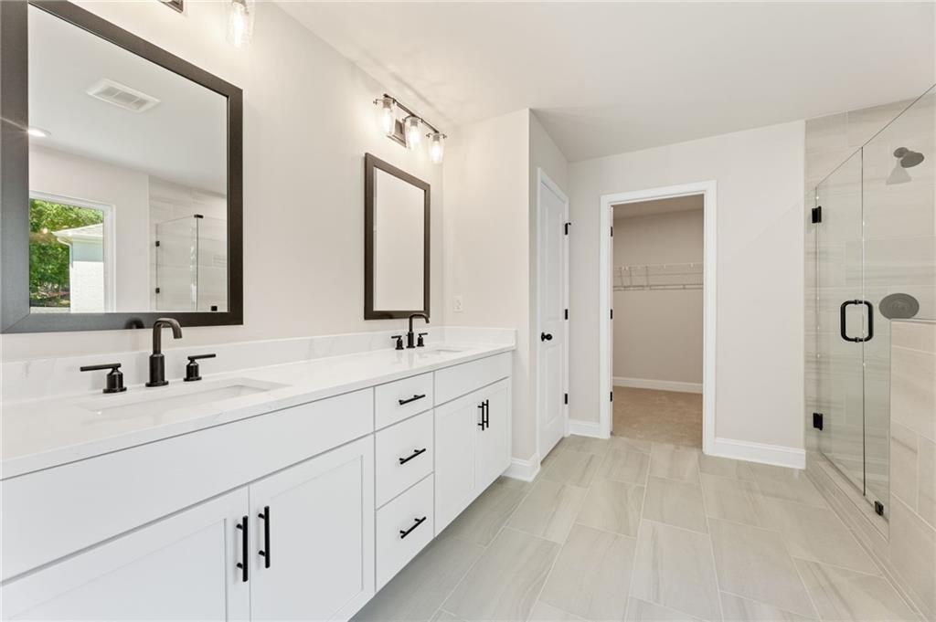 Modern master bath with double white vanity, black faucets, glass shower in Davidson Homes The Hickory E, Buford, GA
