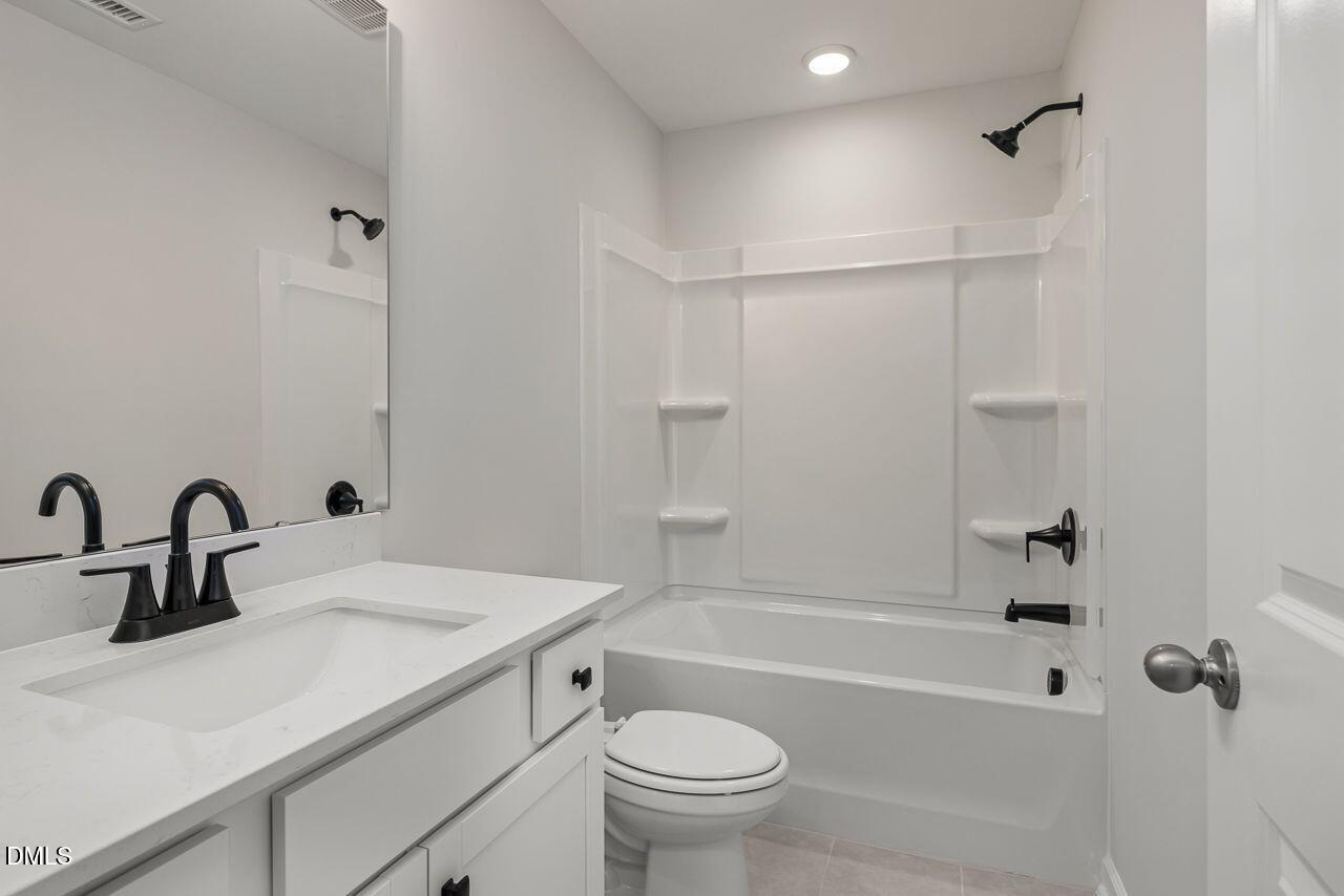Modern bathroom with white vanity, quartz countertop, and tub-shower combo in The Birch II A home in Montrose, Aberdeen.