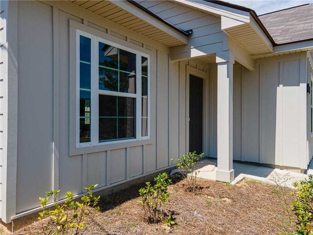 Front exterior of beige-sided 3-bedroom Evermore Homes Washington plan with large window and covered entry in Heatherbrook, Phenix City, Alabama